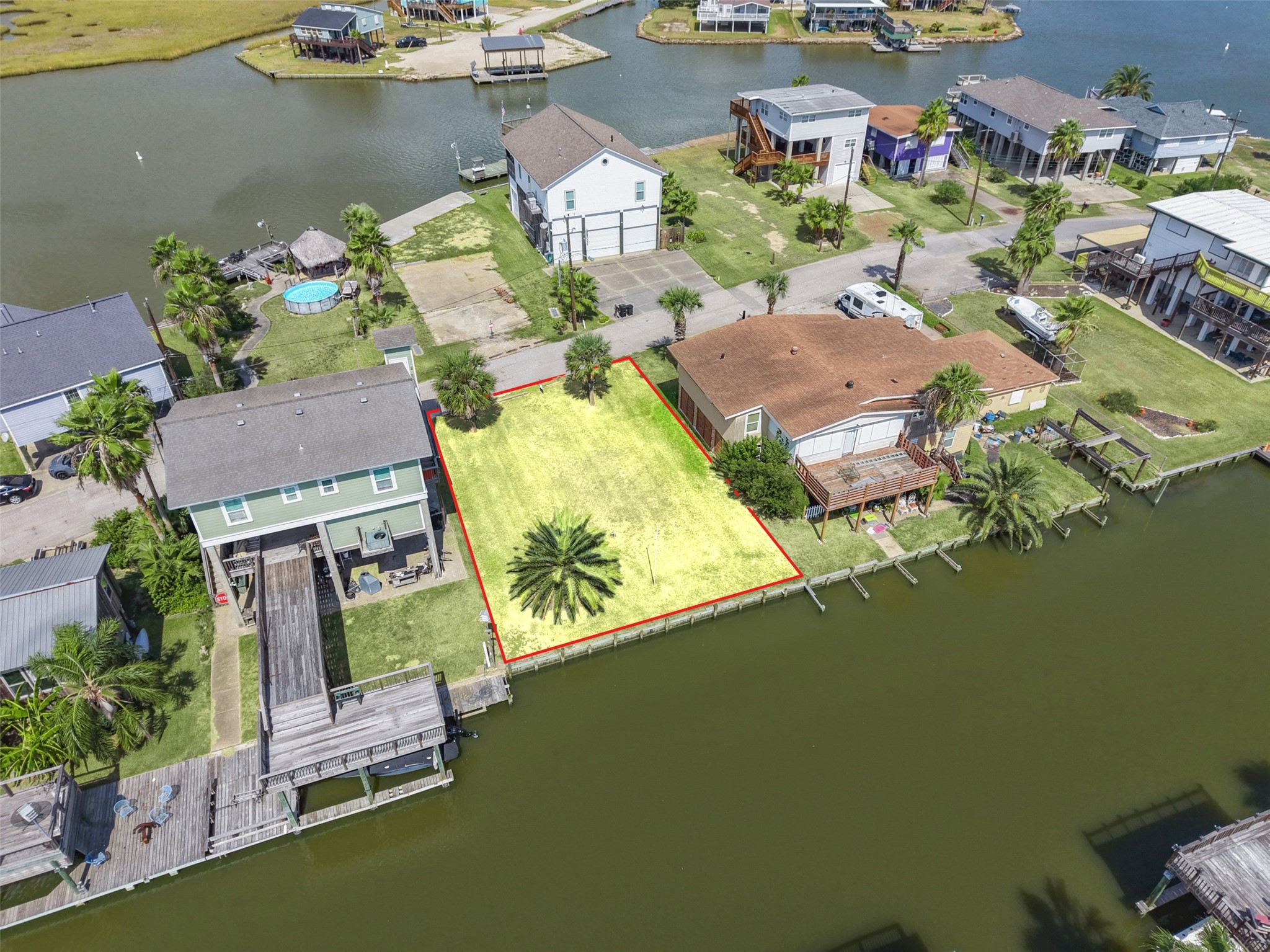 A little farther down the canal. The lot is cleared, with newer construction on both sides, and ready for a build in the same raised style you see all around it.
