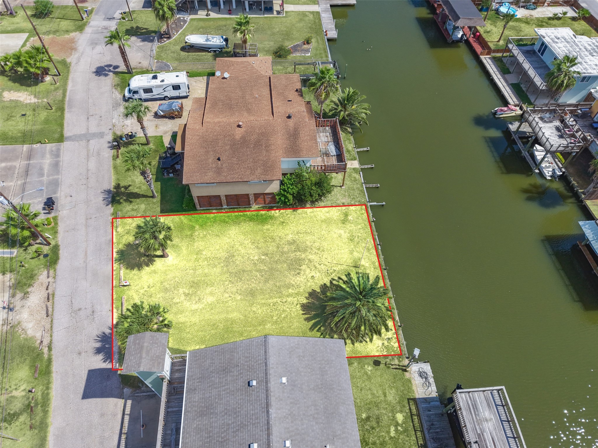 Above the street side. Clean frontage on Lakeside Drive with the neighbors' driveways on either side, leaving room to lay out a drive and parking under the house.