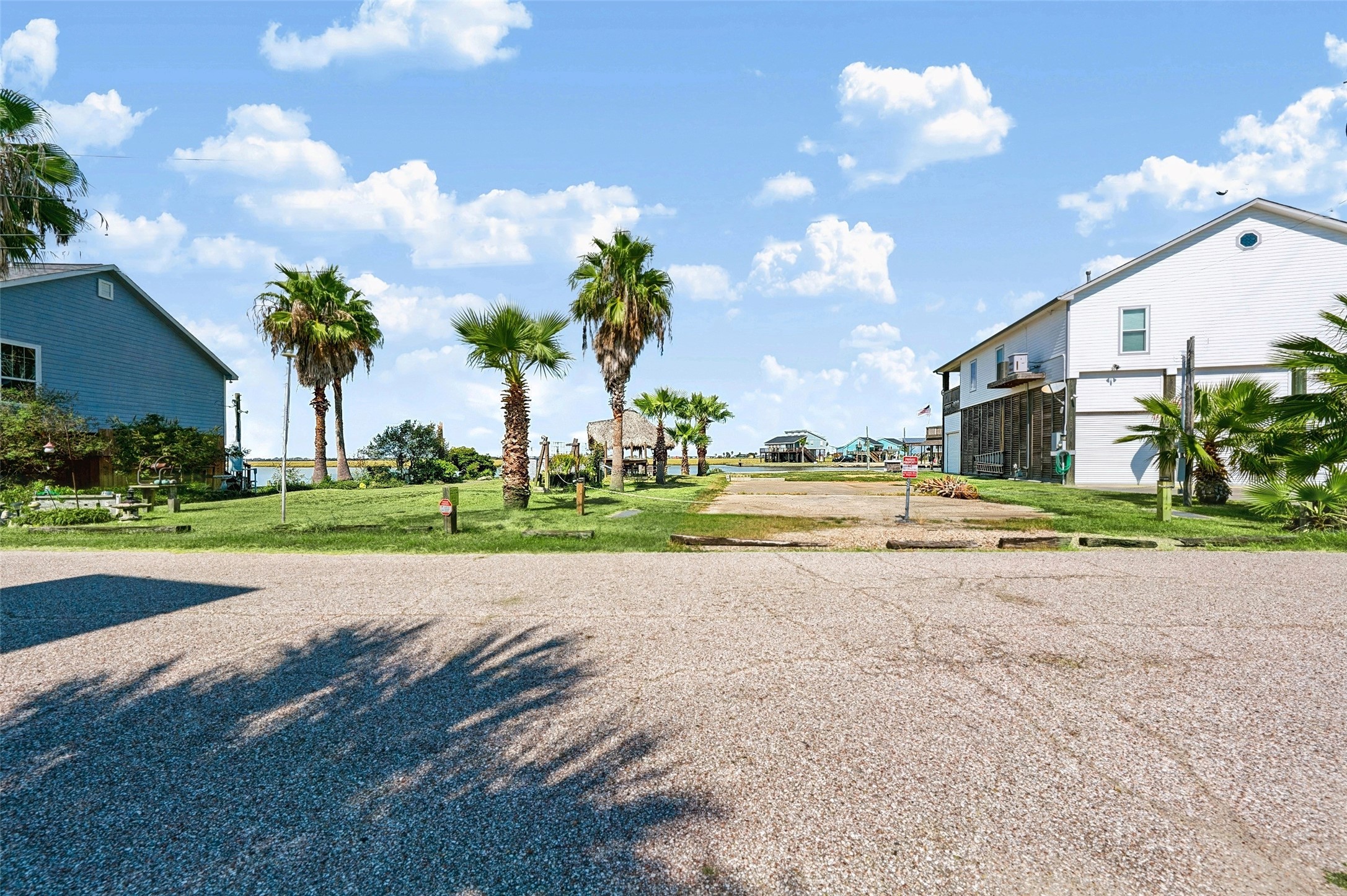 Lakeside Drive out front, with the lot's two Sabal palms joining the palms down the street and open ground across the road where the sunsets show up. Easy to picture your front porch here!