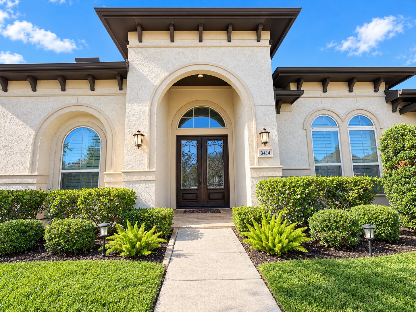 A closer look at the elegant front entrance, highlighting decorative ironwork and beautiful stucco finishes.