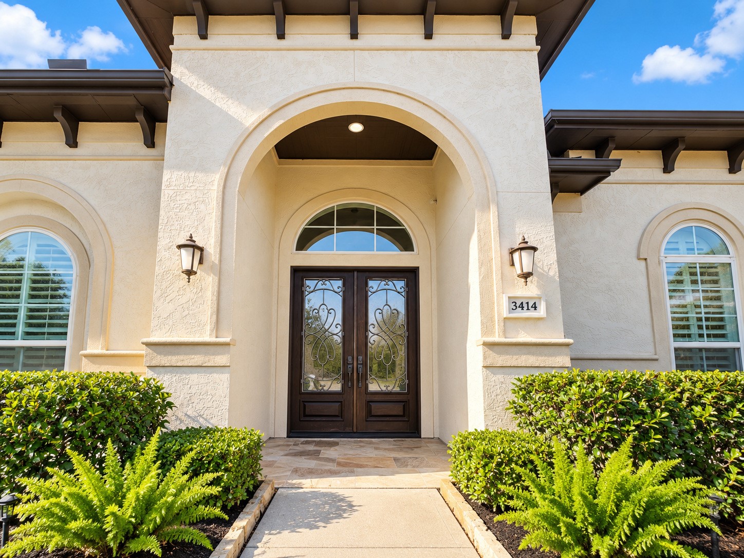 Stunning arched front entry featuring decorative double doors, architectural detailing, and attractive landscaping.