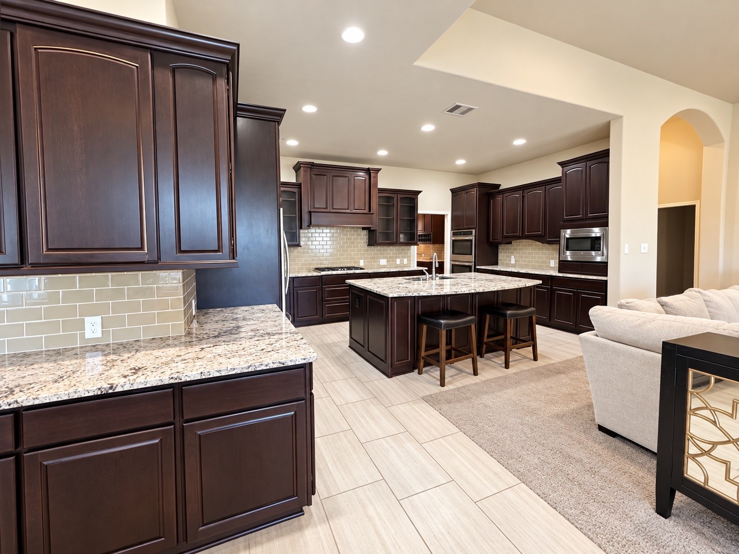 Convenient butler's pantry or serving area featuring rich dark cabinetry, granite countertops, and attractive tile backsplash.