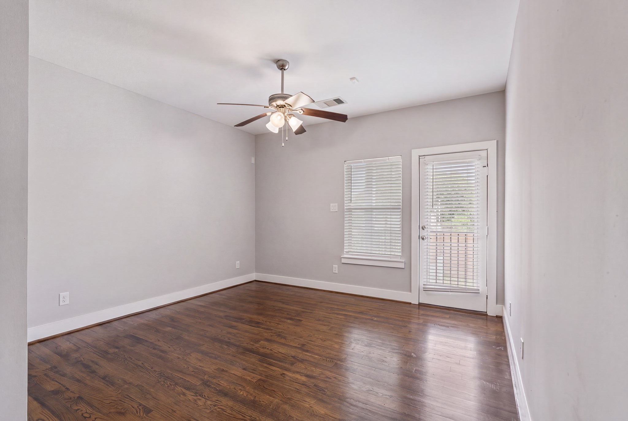 Downstairs bedroom featuring hardwood floors and natural light from the window and exterior door.
