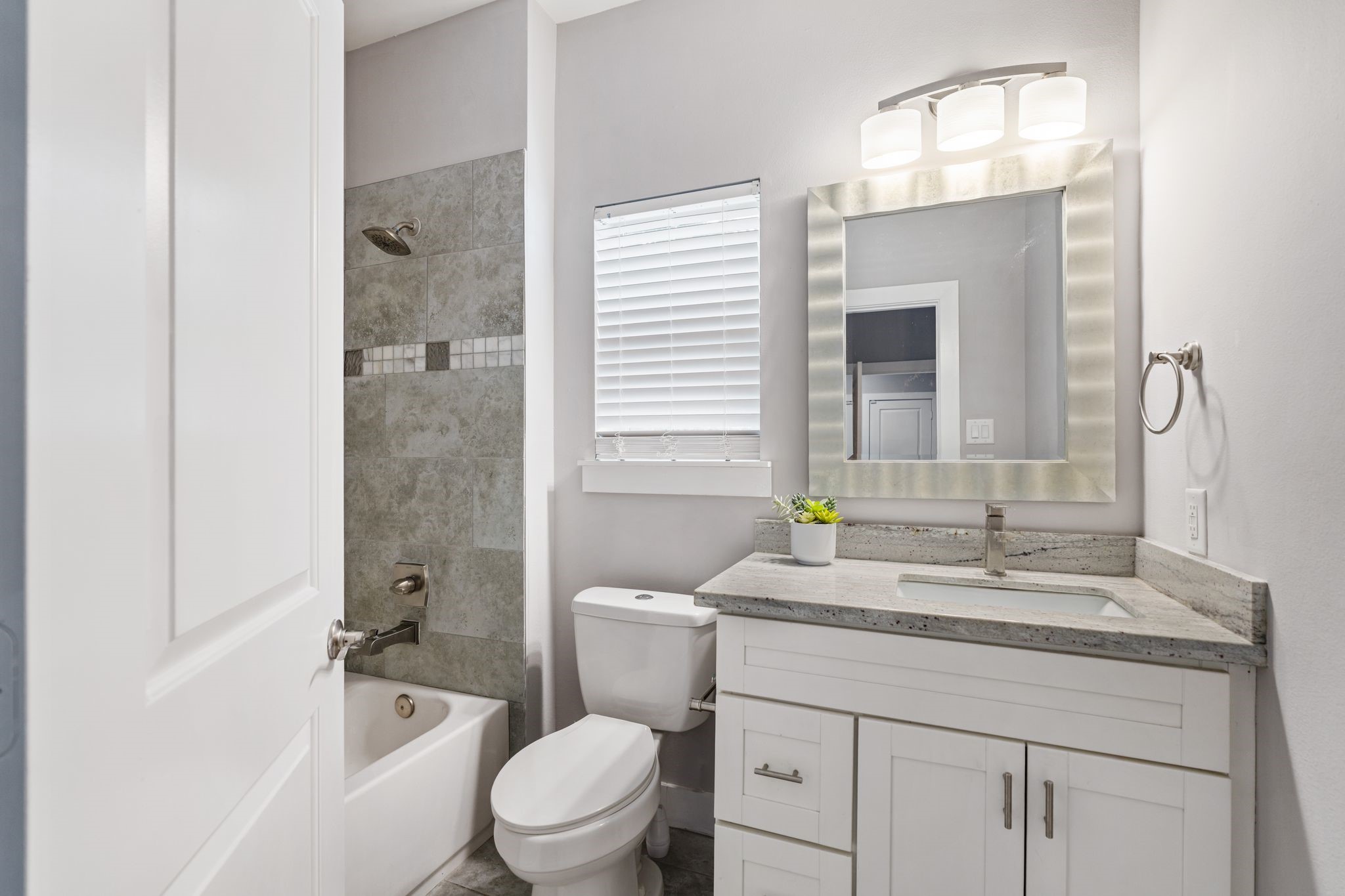 Downstairs bathroom with a vanity, updated fixtures, and a tiled tub and shower surround.