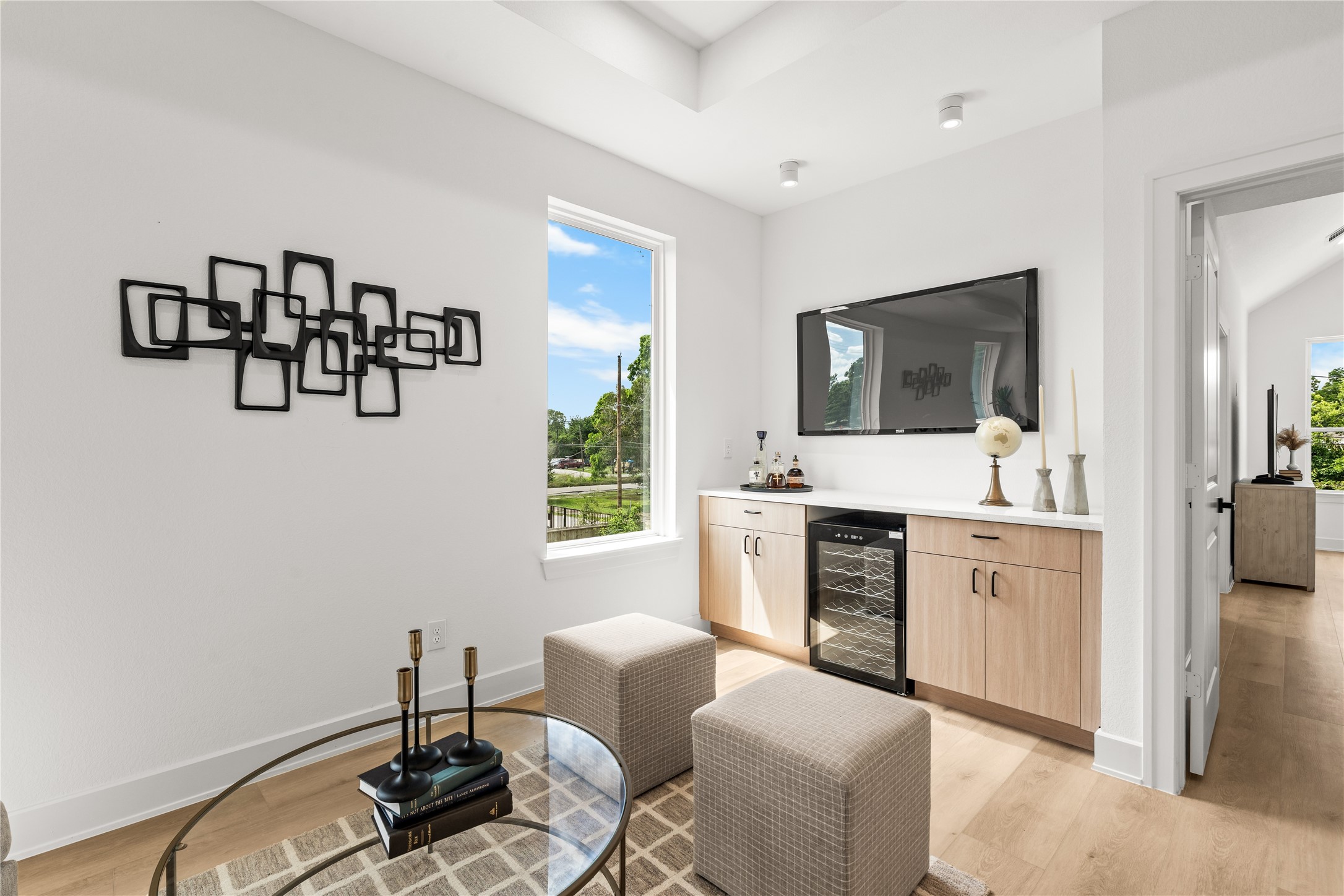 This closer look at the second-floor lounge shows the dry bar and media wall setup. The TV area is placed right above the long countertop, making it easy to host game days. Warm wood cabinets provide plenty of storage.