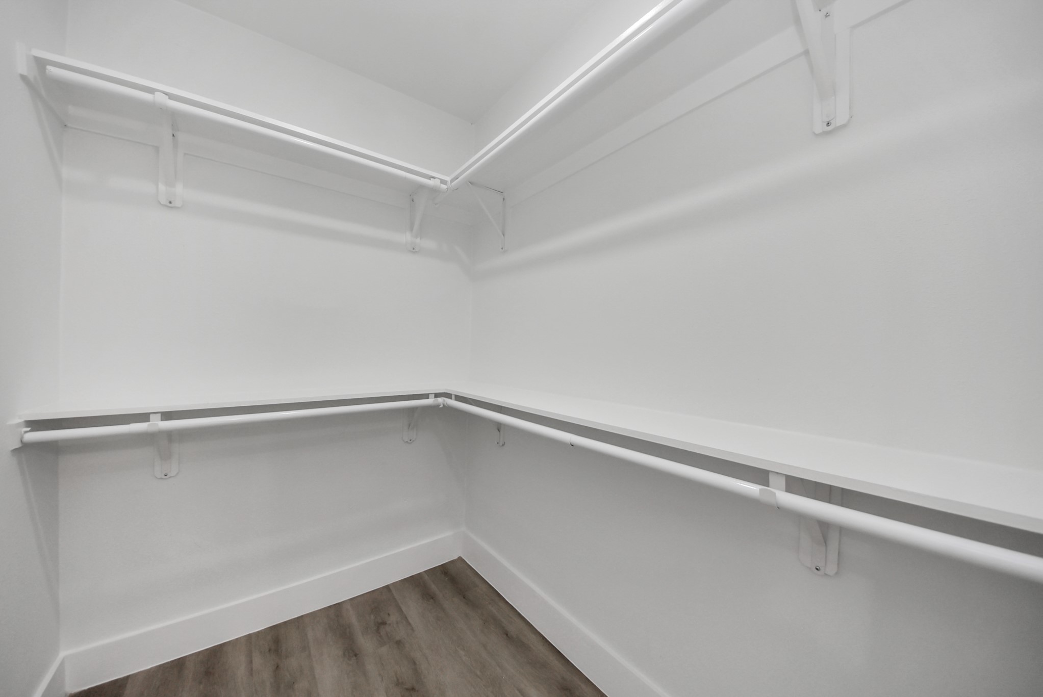 Spacious walk-in closet featuring sleek white shelving and ample hanging space.