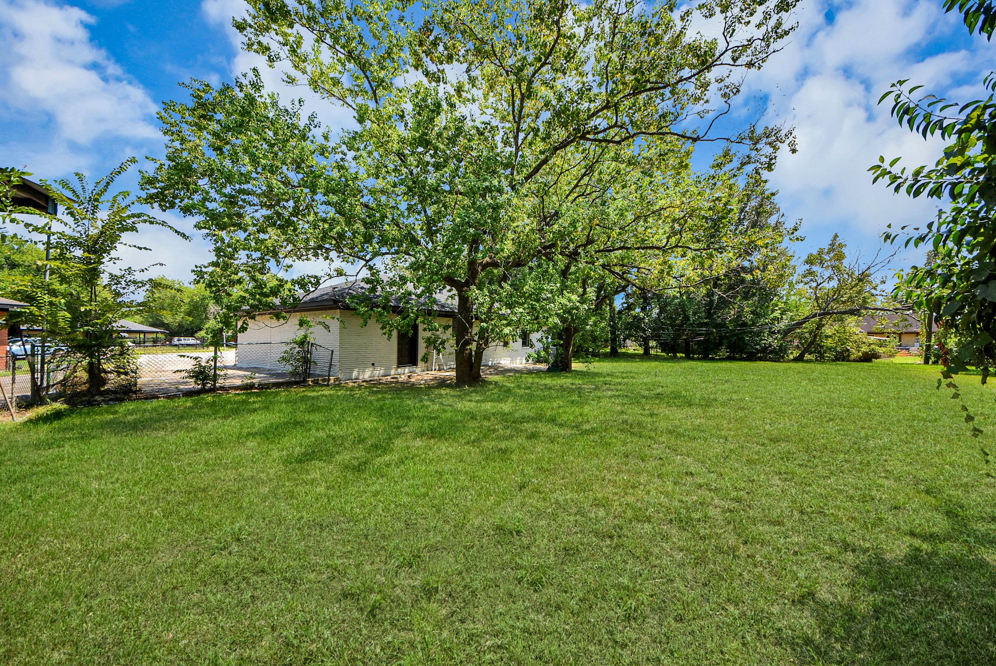 Expansive, lush backyard with mature trees offering shade and privacy, perfect for outdoor activities and relaxation.