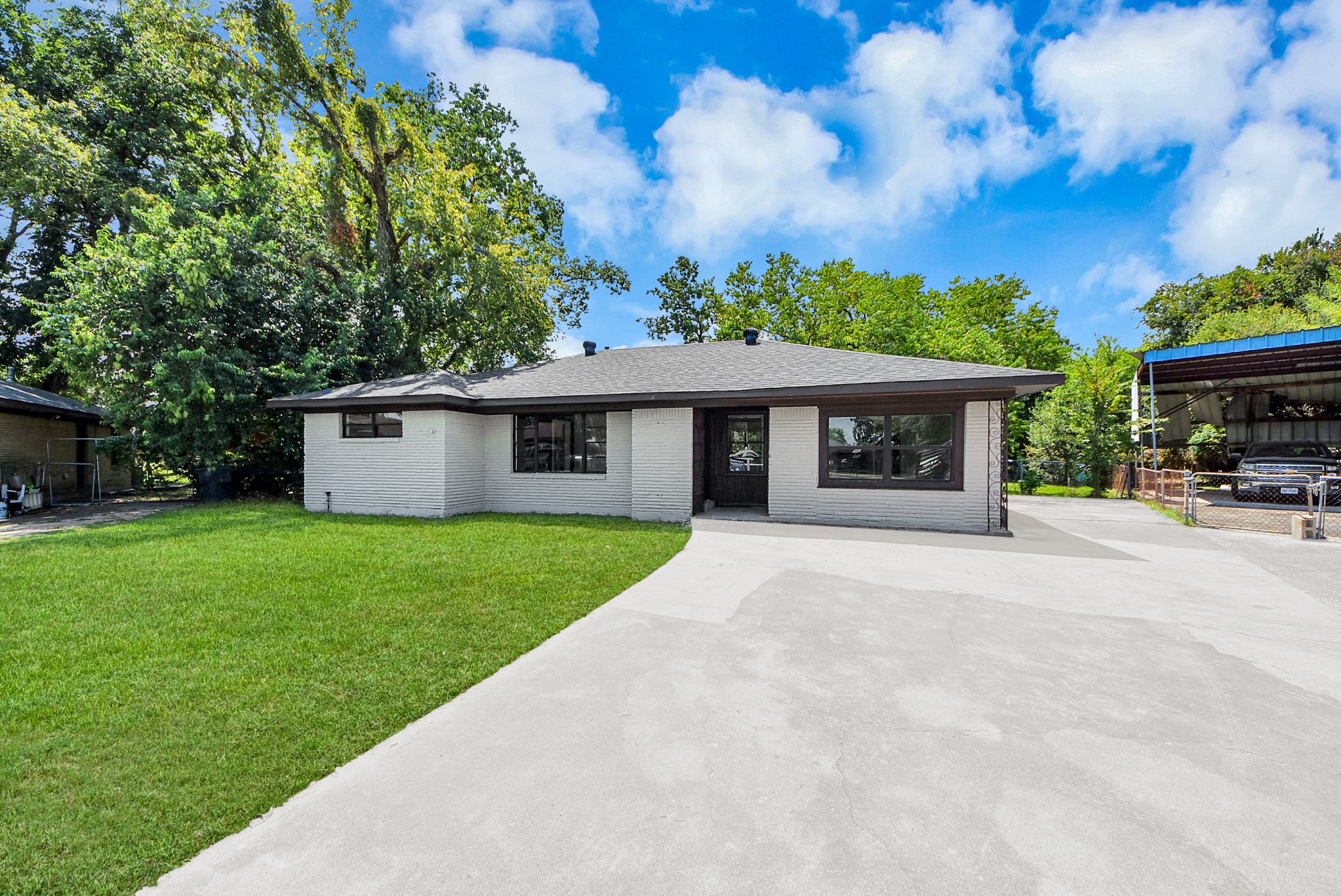 Charming single-story home with a modern exterior, set on a spacious lot with lush greenery and ample driveway space.