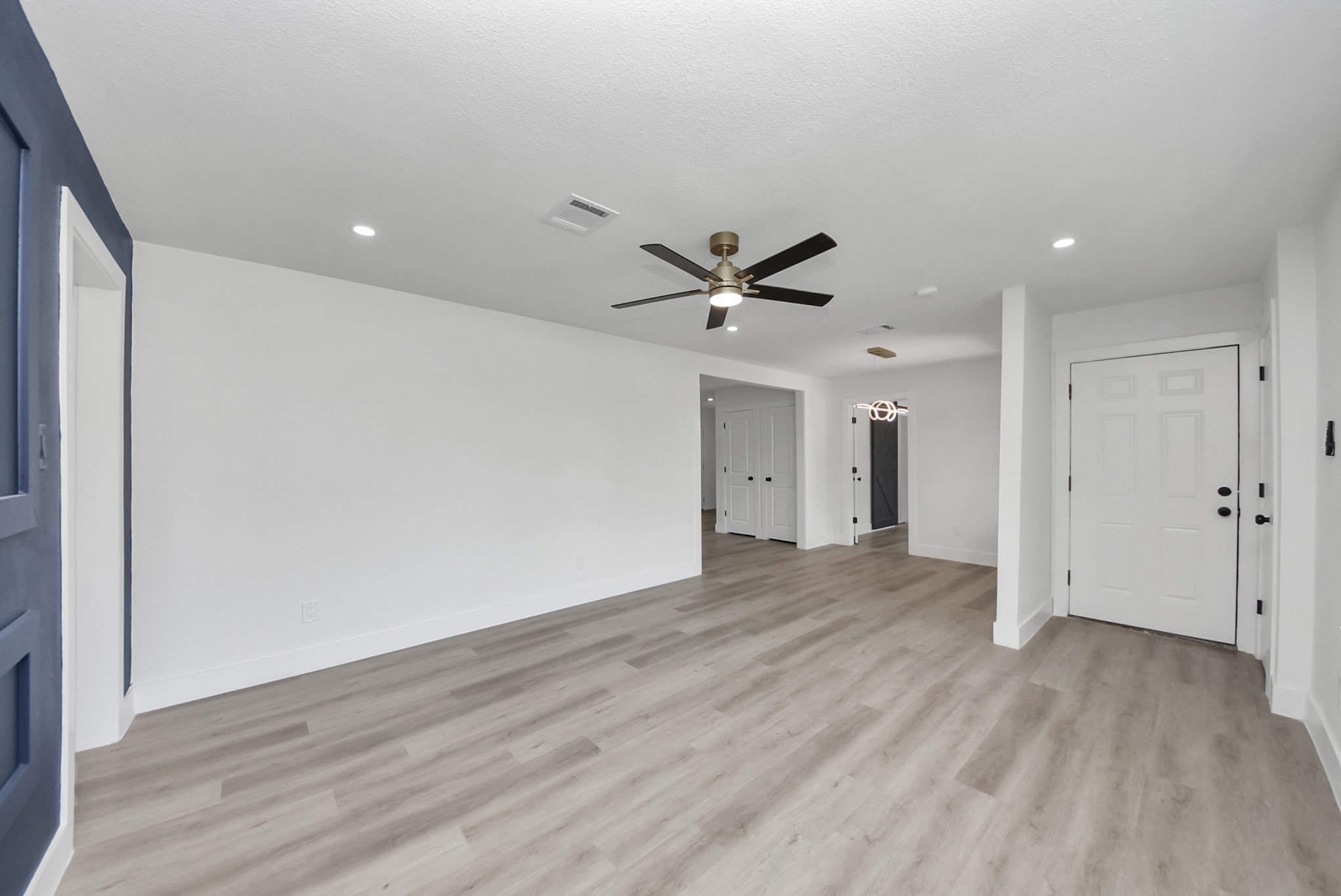 Bright, open living area with modern flooring, recessed lighting, and a stylish ceiling fan, offering a welcoming space for relaxation and entertaining.