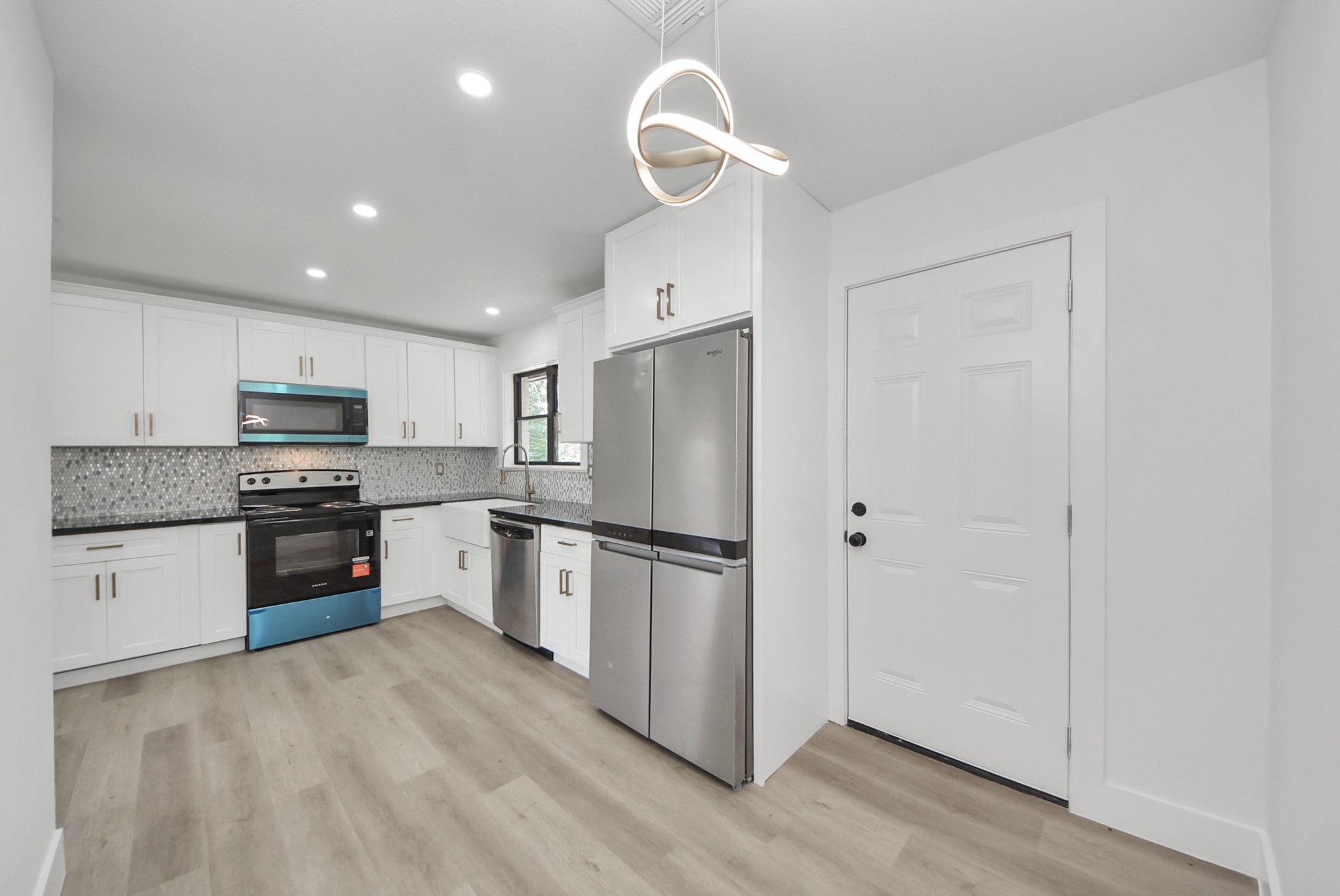 Modern kitchen with sleek stainless steel appliances, elegant white cabinetry, and a stylish geometric backsplash.