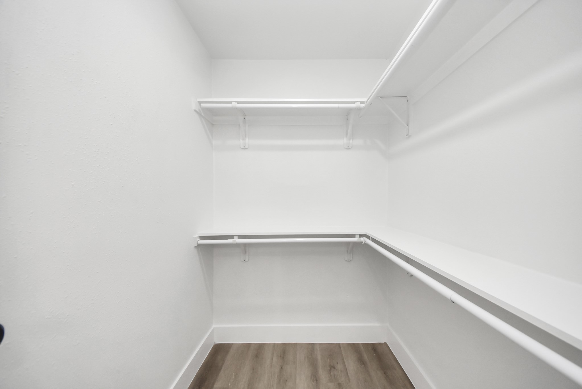 Spacious walk-in closet with ample shelving and hanging space, featuring a modern, clean design and elegant wood flooring.