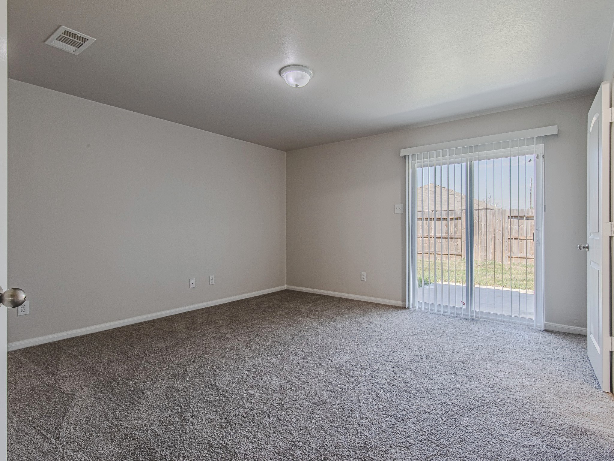 The primary bedroom offers comfortable proportions, carpet flooring, a ceiling fan, and windows overlooking the backyard.