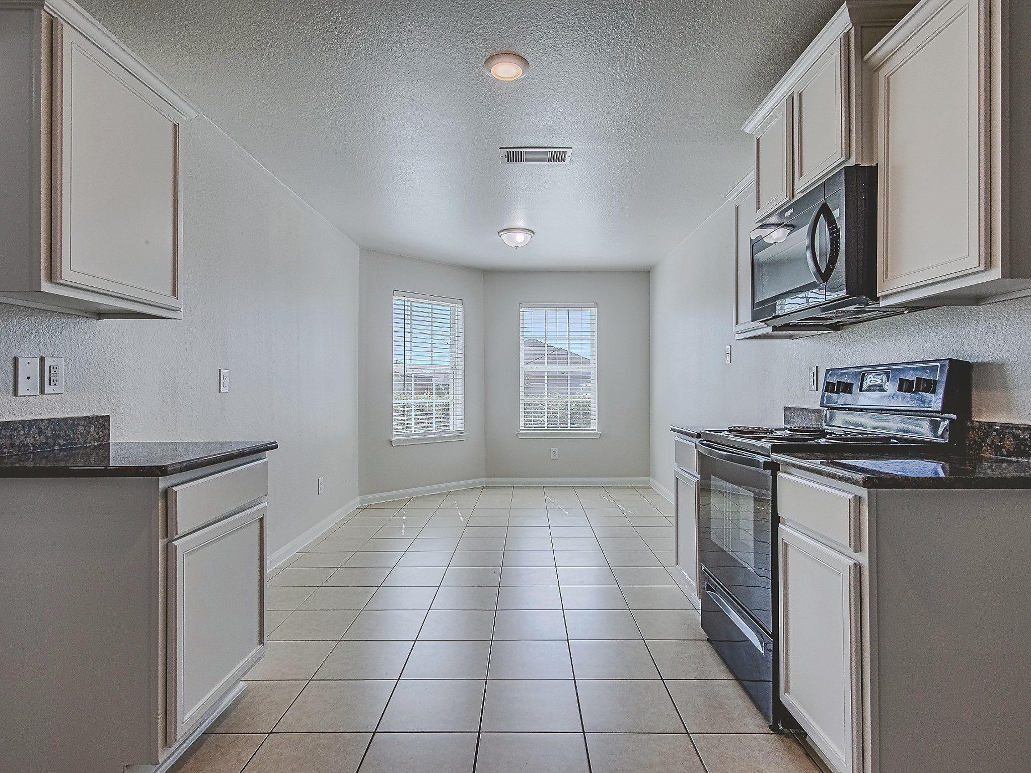 A view through the kitchen highlights its efficient layout and adjoining window-lined dining nook.