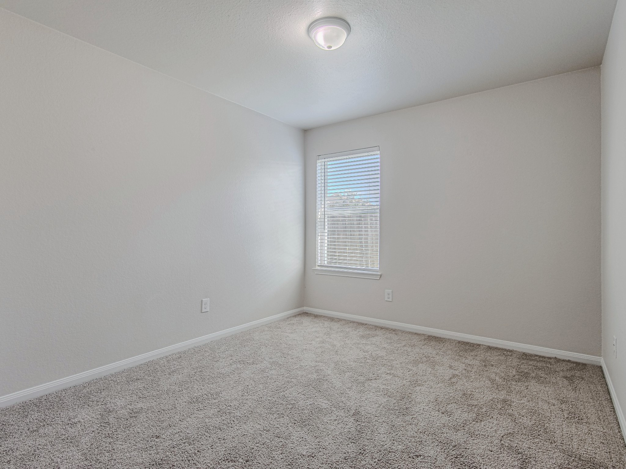 This secondary bedroom features carpet flooring, neutral walls, and a window that brings in natural light.
