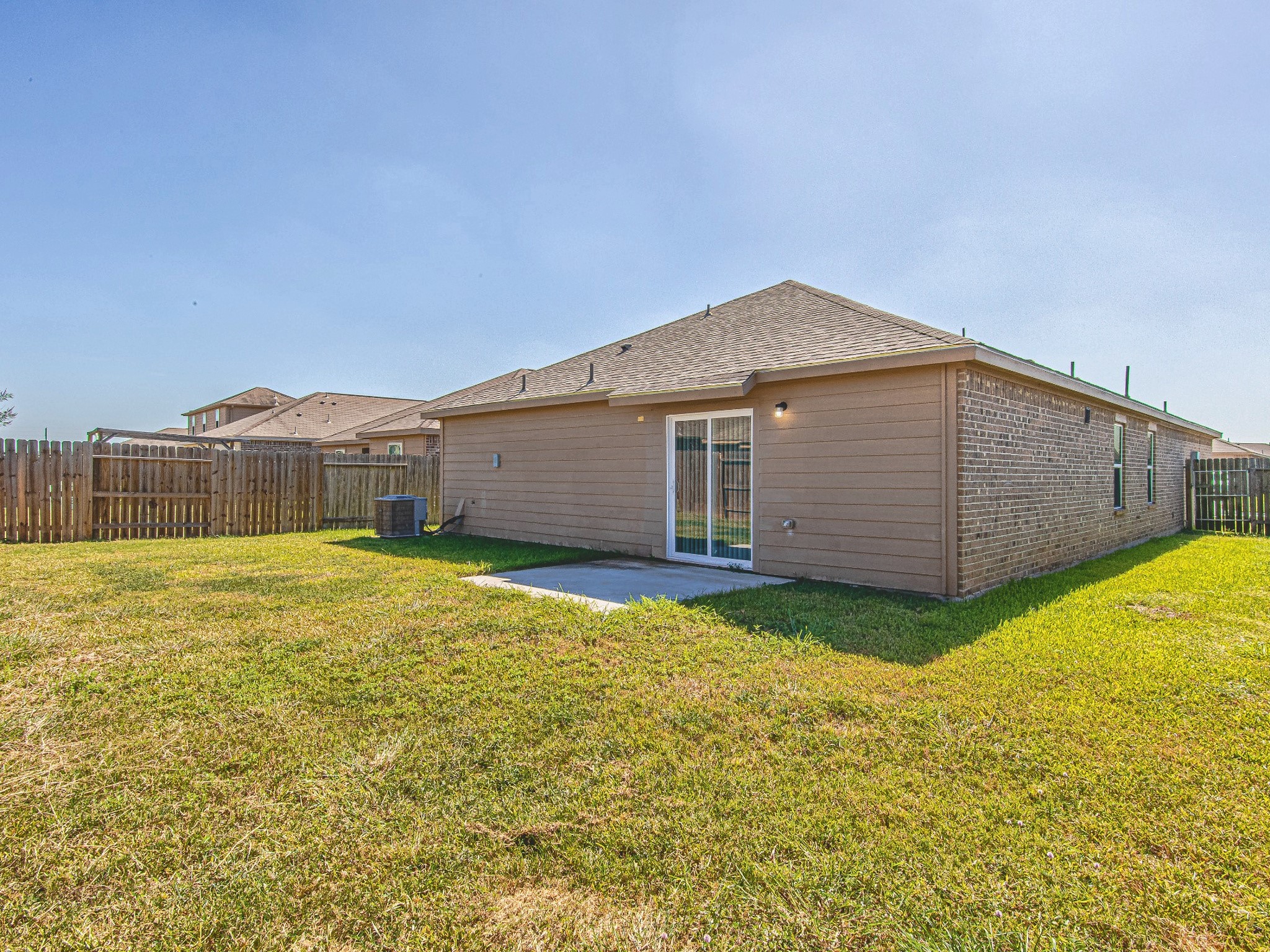The rear exterior features direct backyard access and a concrete patio, with lawn space ready for your outdoor plans.