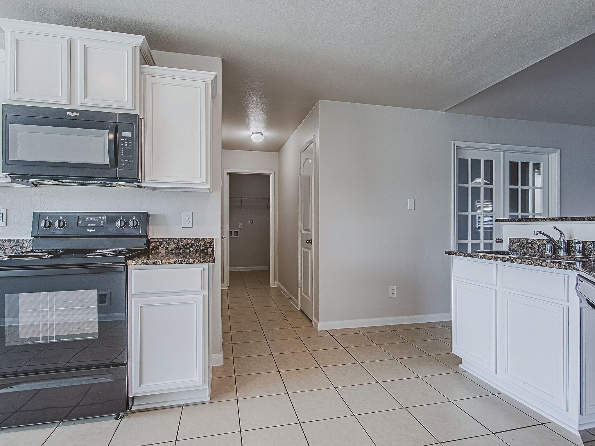 A range and built-in microwave pair with granite work surfaces and upper and lower cabinets to create a practical cooking space.