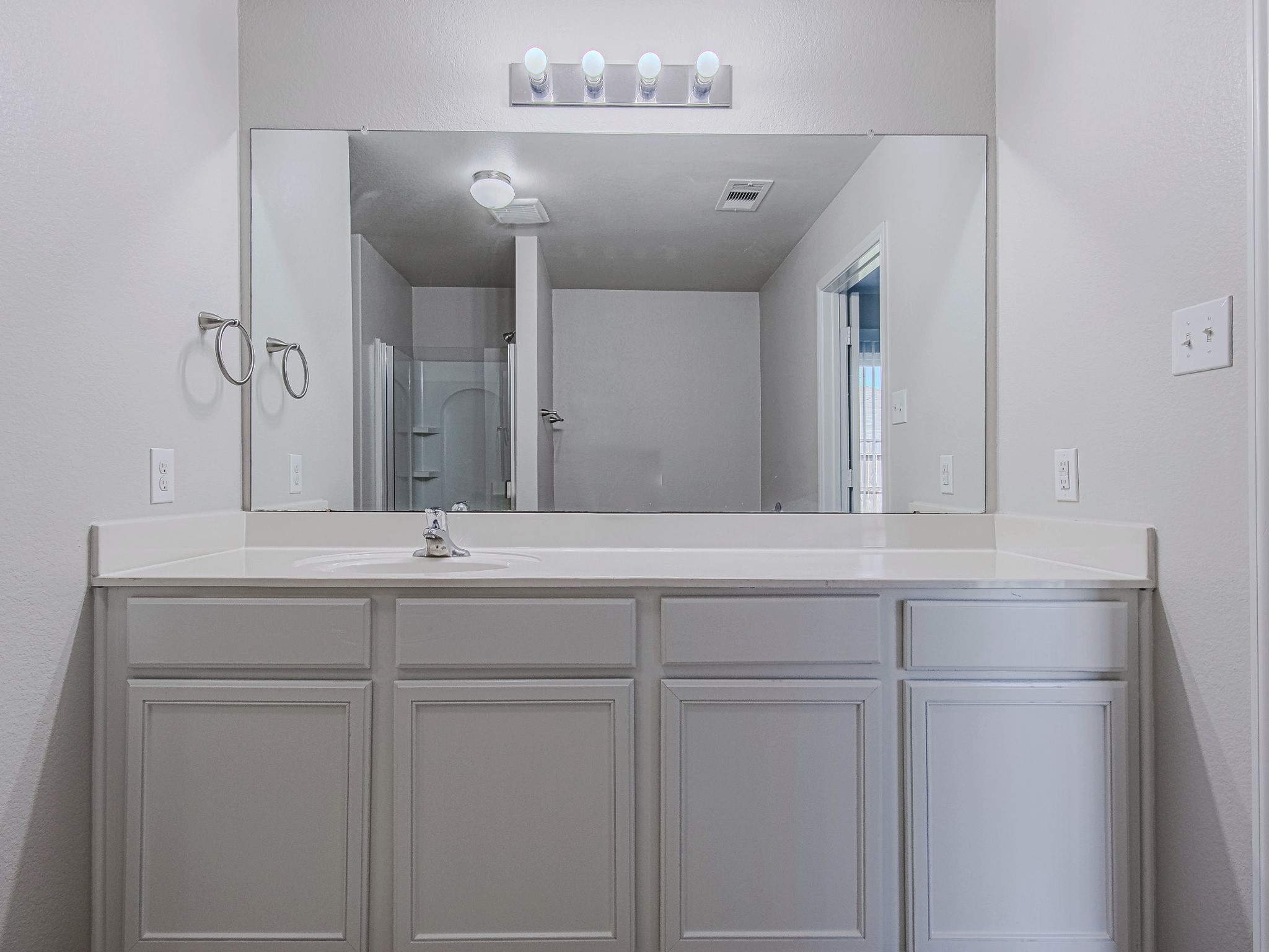 A closer look at the primary vanity showcases its expansive countertop, wide mirror, and storage for daily essentials.