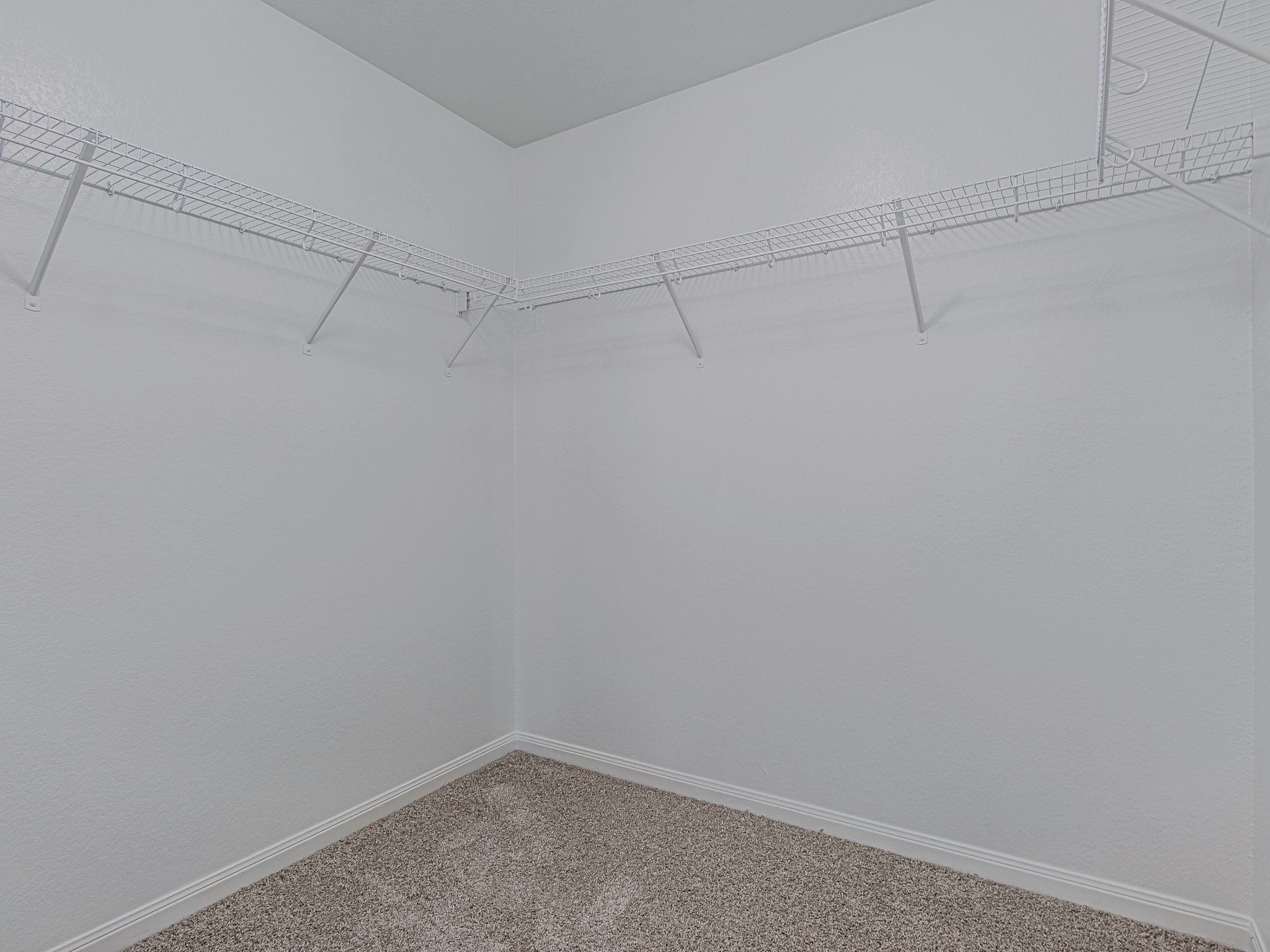 The walk-in closet features wraparound shelving and hanging rods to keep clothing and accessories organized.