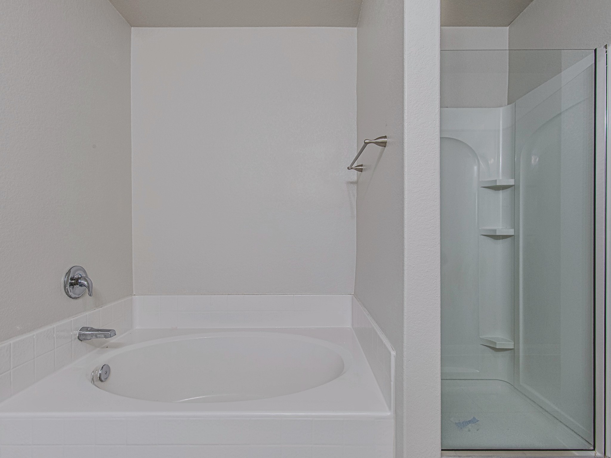 A soaking tub and separate glass-enclosed shower offer two options for unwinding in the primary bathroom.