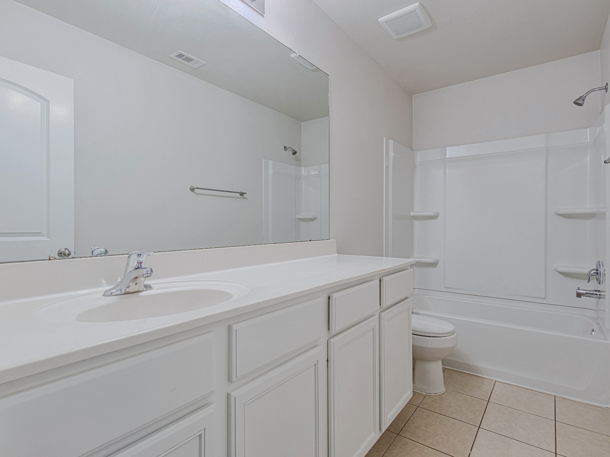 The secondary bathroom includes a vanity with cabinet storage, a wide mirror, and a tub-and-shower combination.