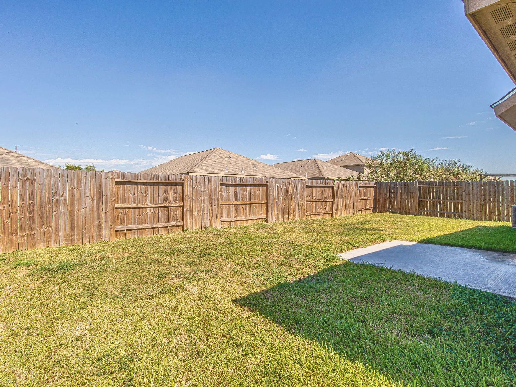 The fully fenced backyard features an open lawn and a concrete patio, providing space for outdoor seating and weekend gatherings.
