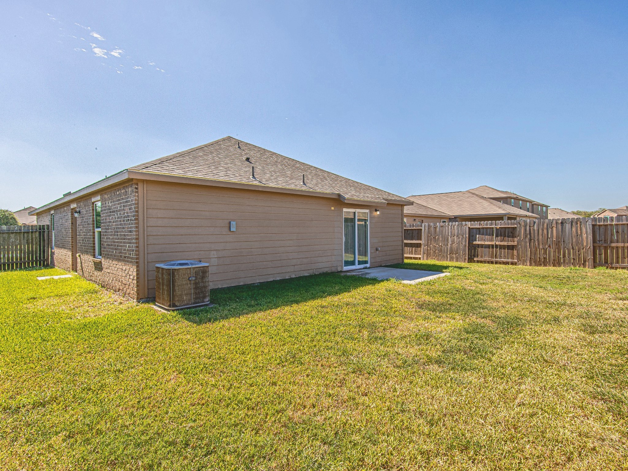A wide backyard view highlights the grassy outdoor space and wood privacy fencing surrounding the property.