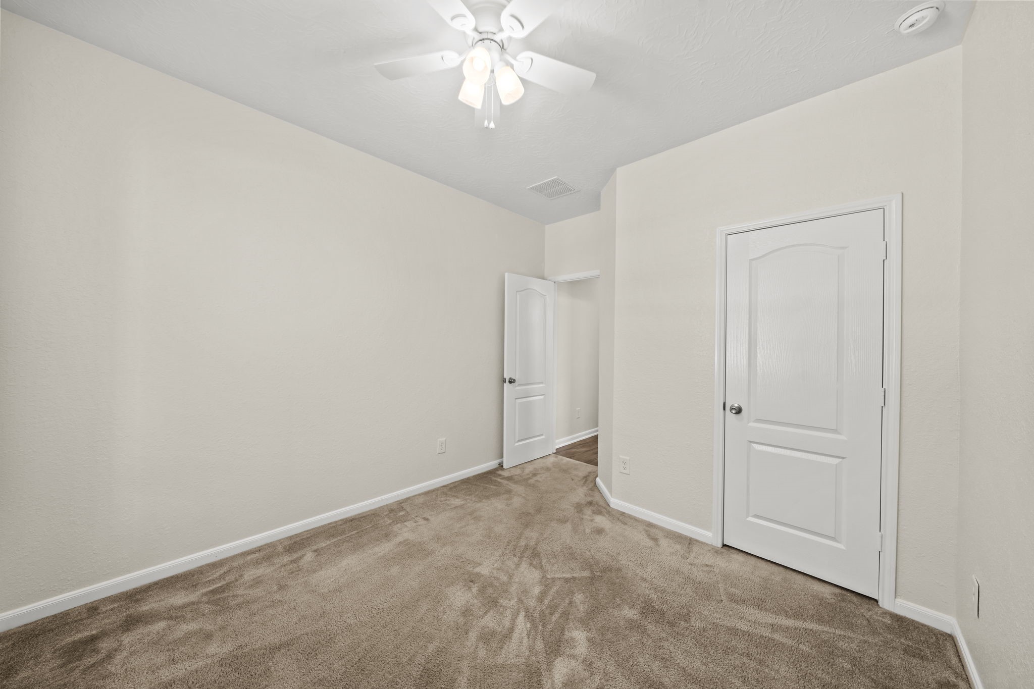 Secondary bedroom featuring neutral carpet, a ceiling fan, and a spacious closet.