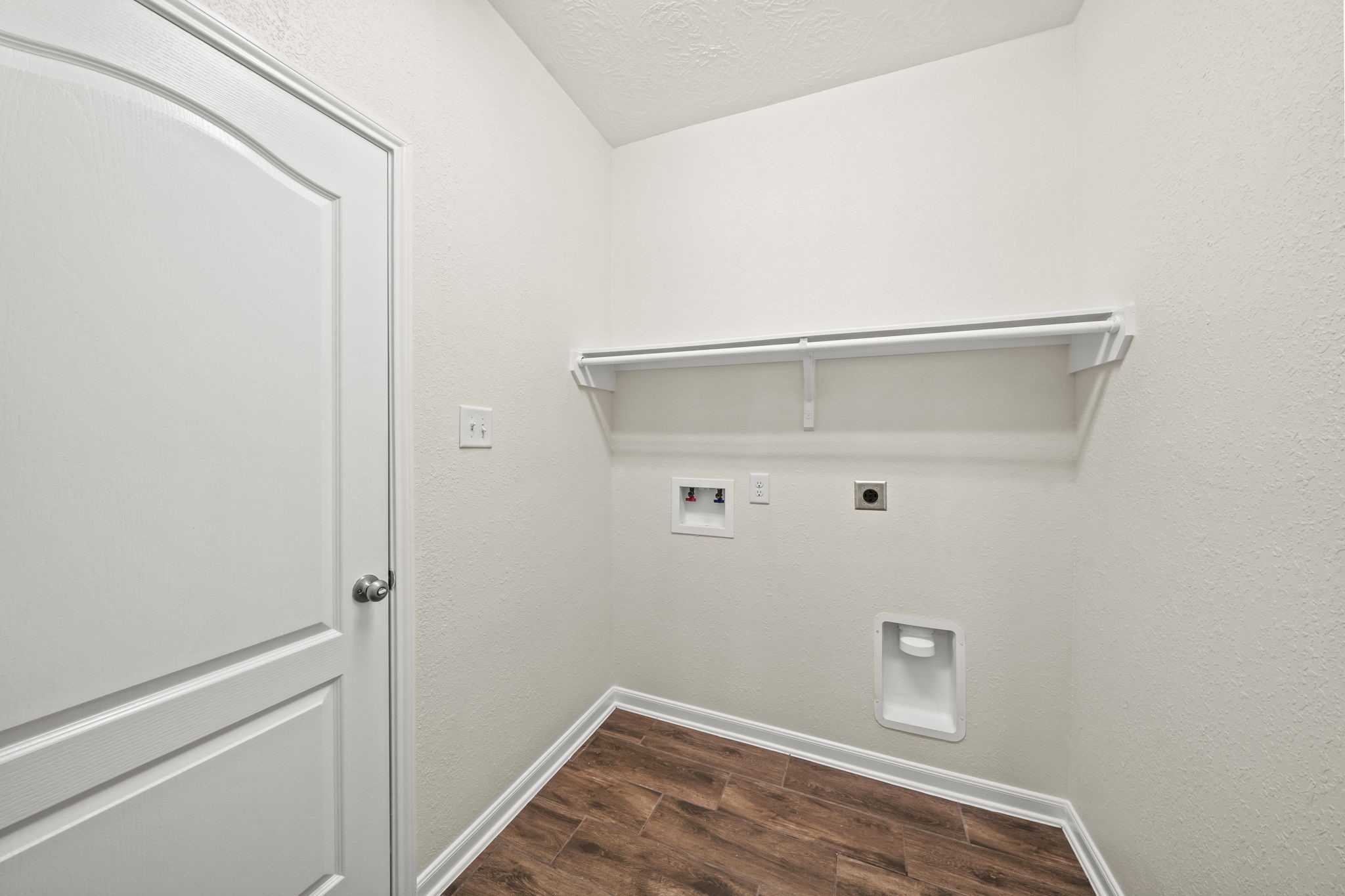 Convenient in-house laundry room with full wood-look tile flooring, and built-in upper shelving for supply storage.