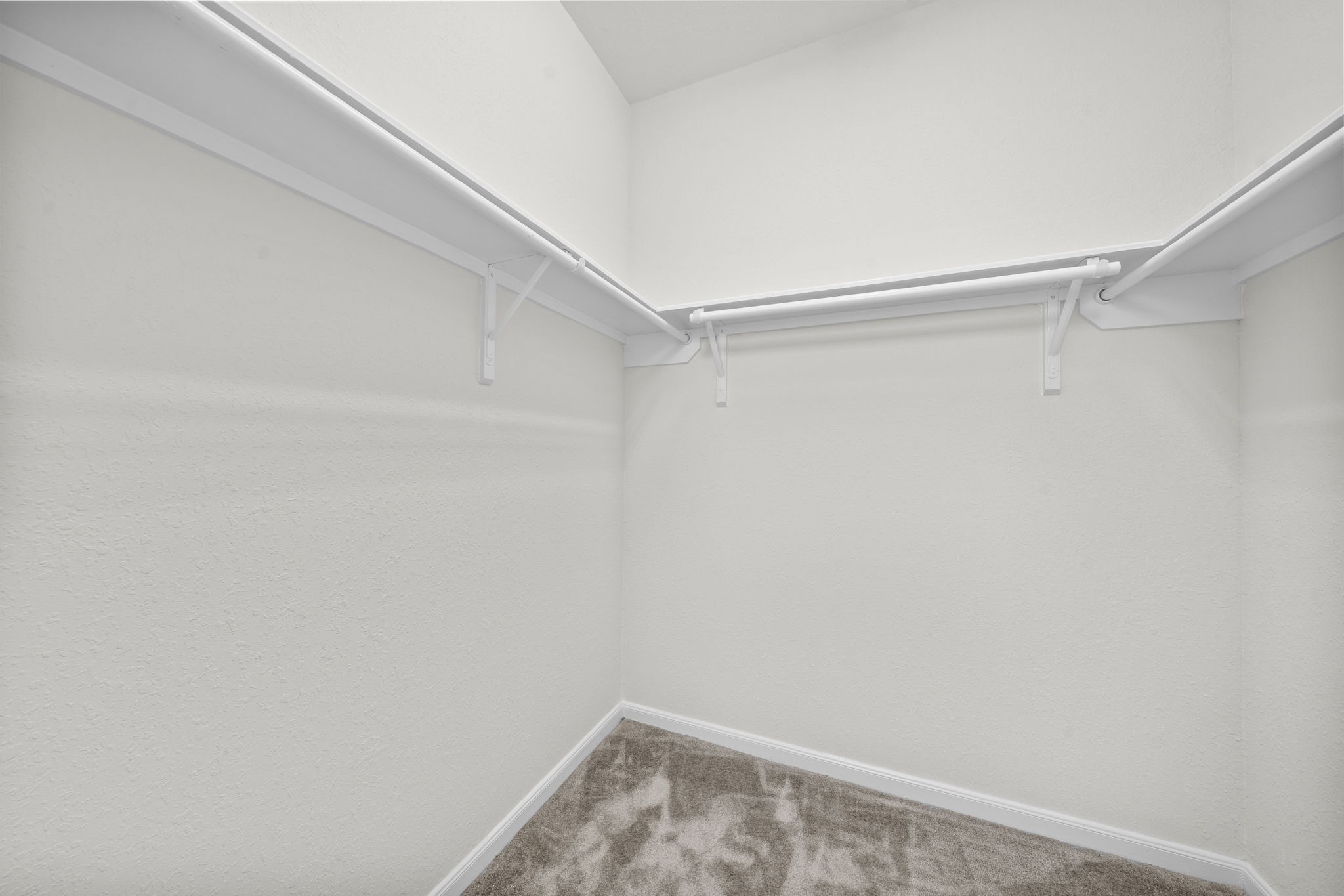 Spacious walk-in closet featuring built-in hanging rods and upper shelving.