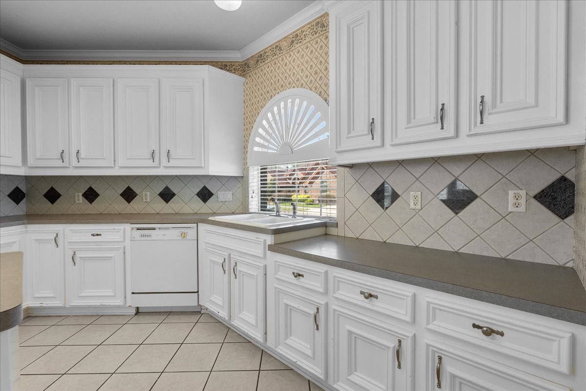An arched window directly over the double-basin sink pours cheerful natural daylight across the workspace.