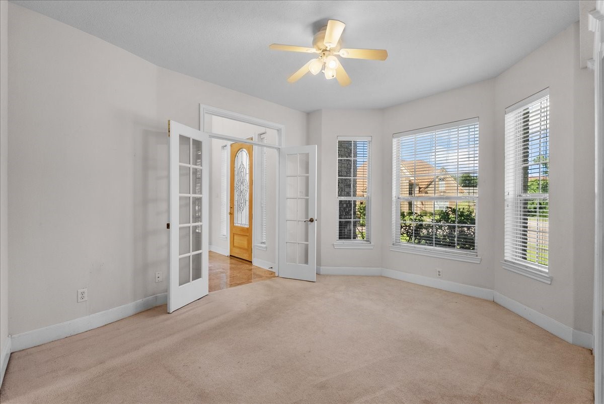 Double French doors open to this versatile front room, ideal for an executive home office, study, or quiet formal living space.