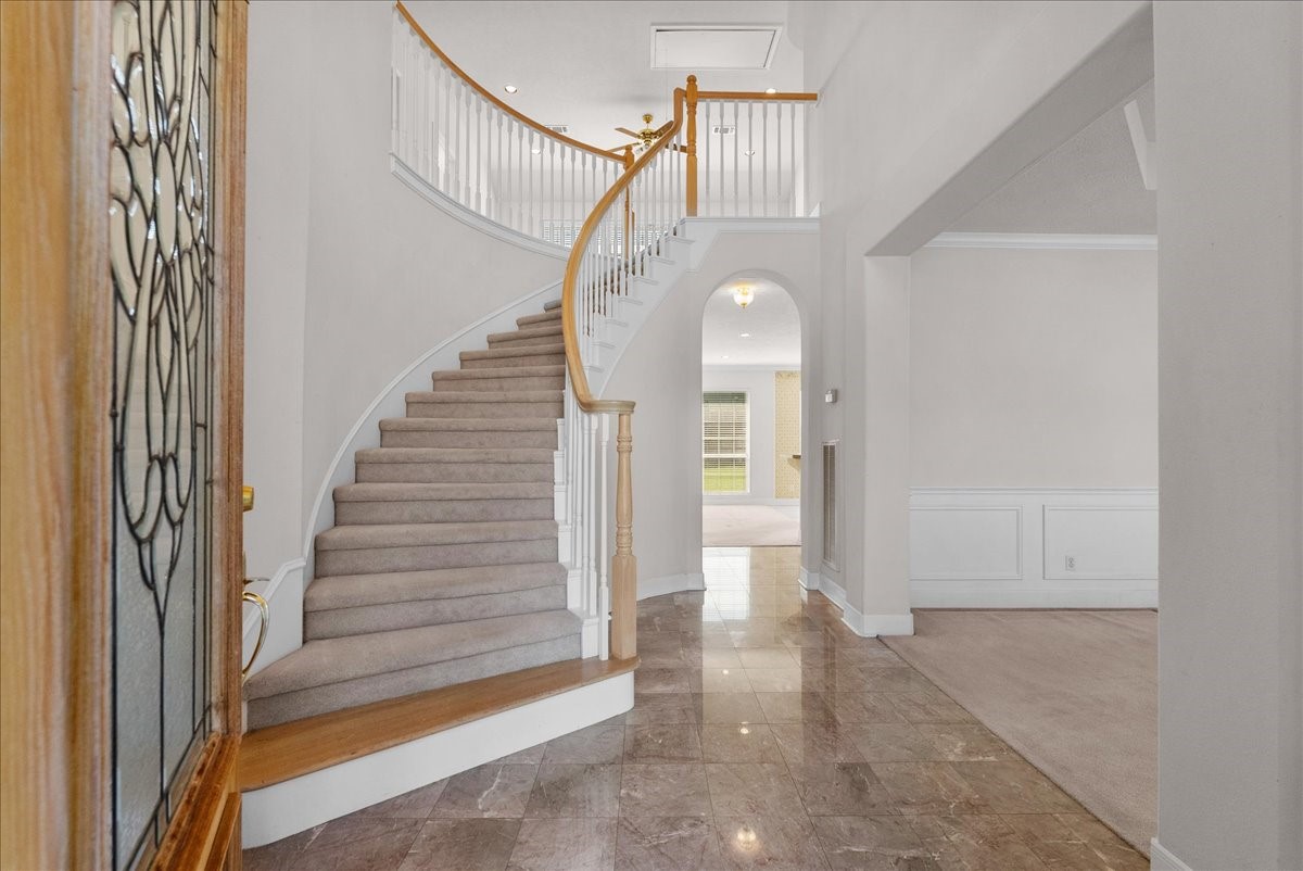 Grand two-story foyer featuring polished tile flooring and a sweeping curved staircase.