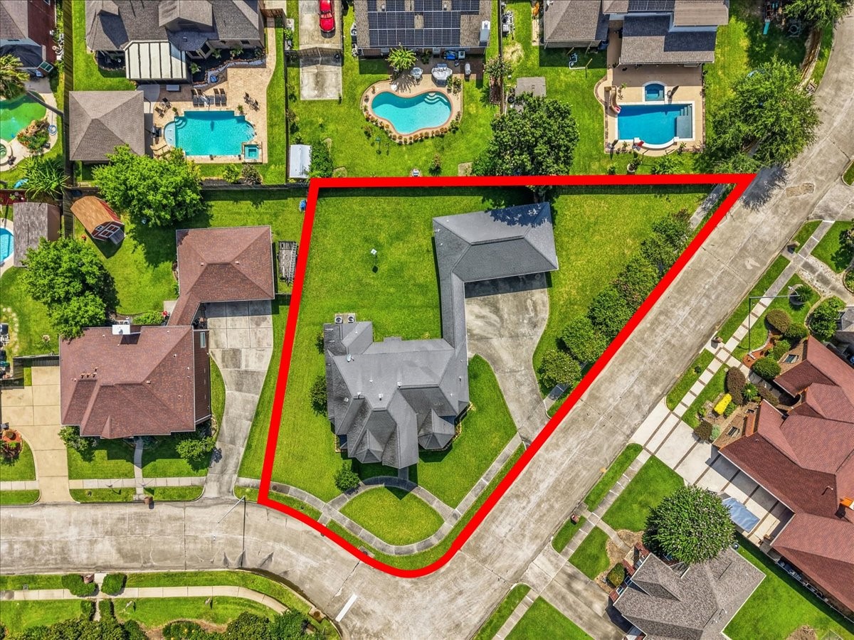 Aerial property view illustrating the generous lot boundaries, extensive driveway parking, and prime corner placement within Country Club Oaks.