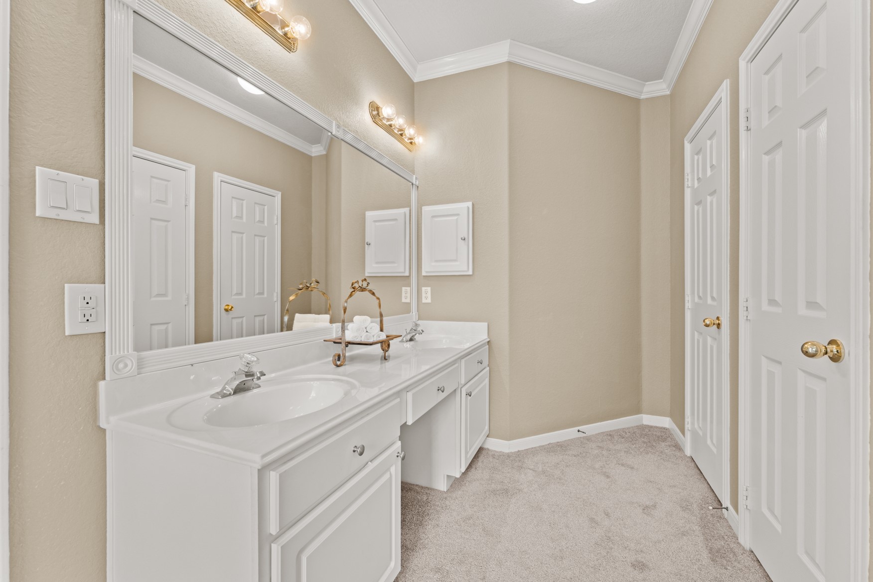 The primary bathroom also features double sinks and cabinetry with a vanity area in the middle, a long framed mirror, linen storage and a private WC.