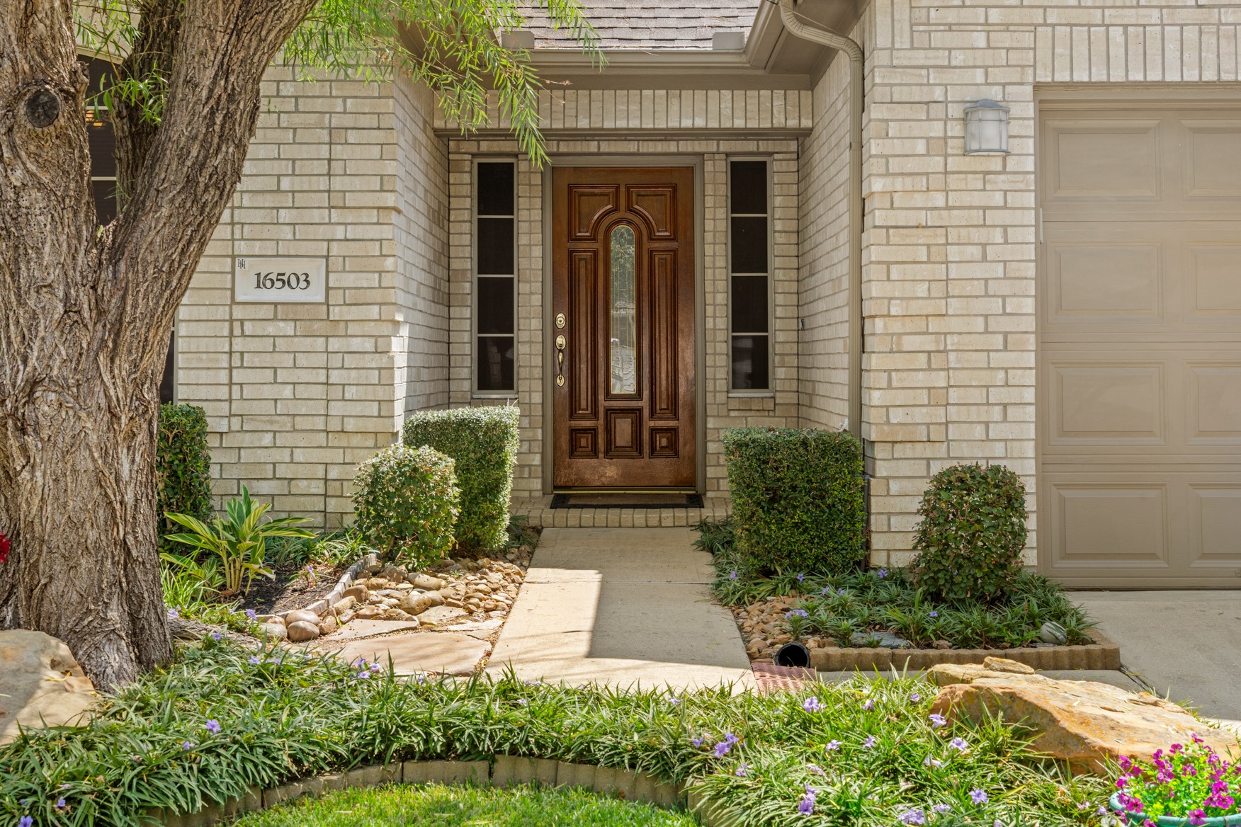 A welcoming entrance with stone-lined pathways and mature landscaping!