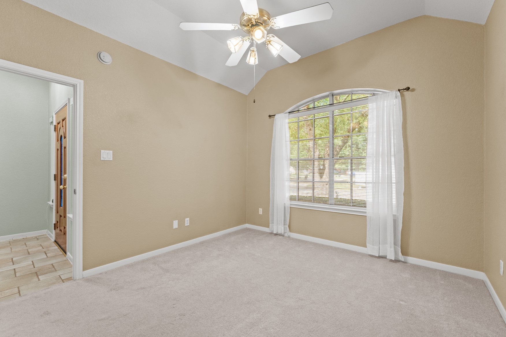 This is the first guest bedroom featuring a wide arched window overlooking the front yard and a high vaulted ceiling.  This room would also make a great office with a nice view!