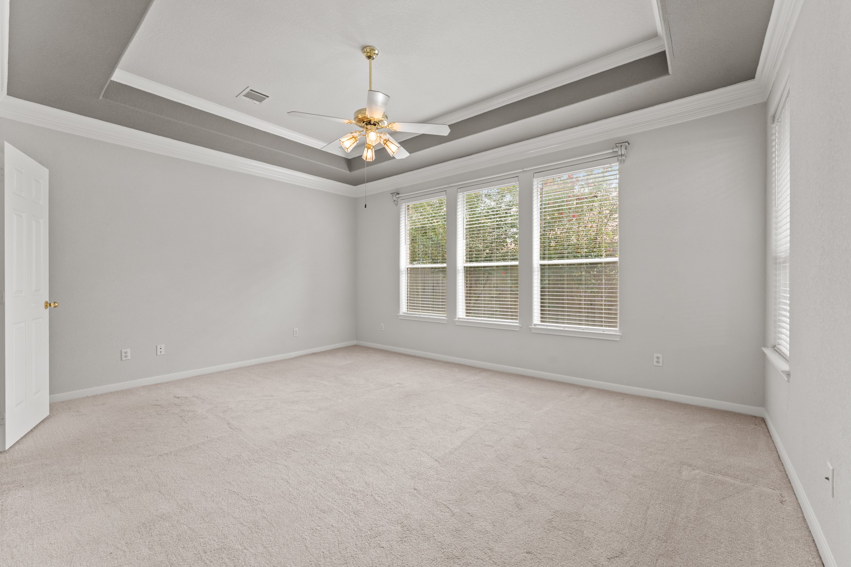 This primary suite is a true private retreat! The tray ceiling and elegant crown molding help create a luxurious feel to the space.