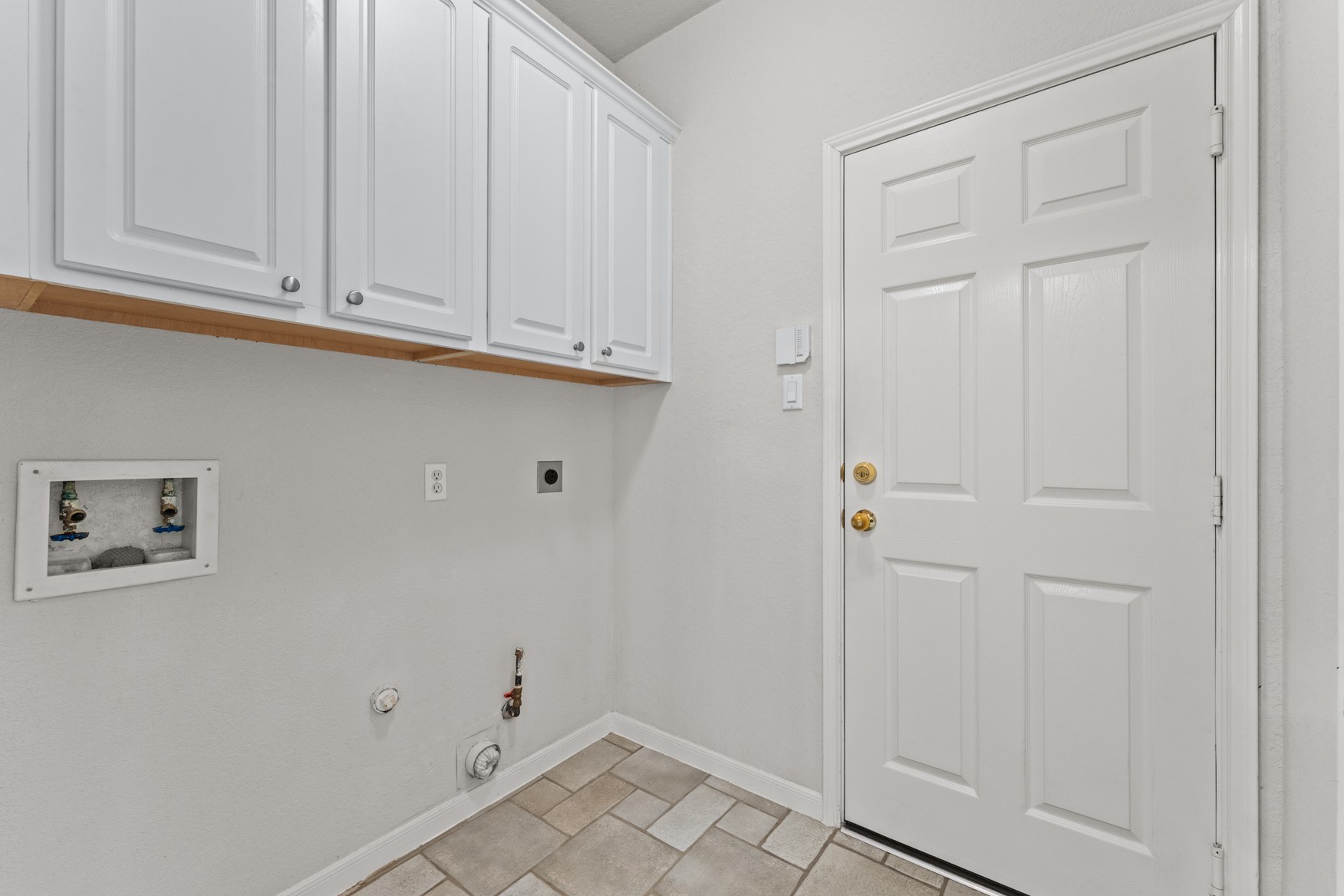 Laundry room with storage cabinets and both gas and electric dryer connections.