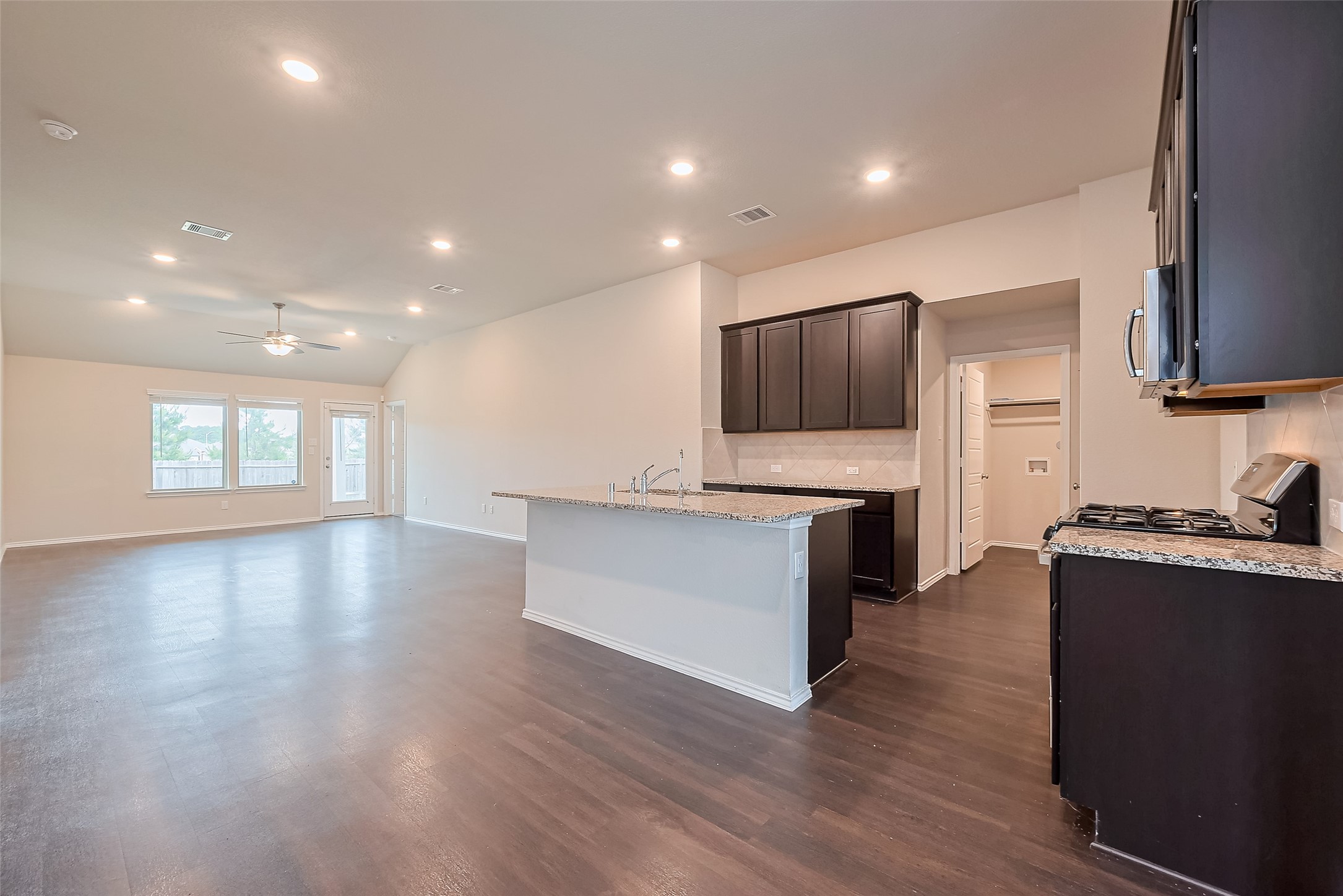 Open kitchen with granite counters, stainless appliances and gas range.