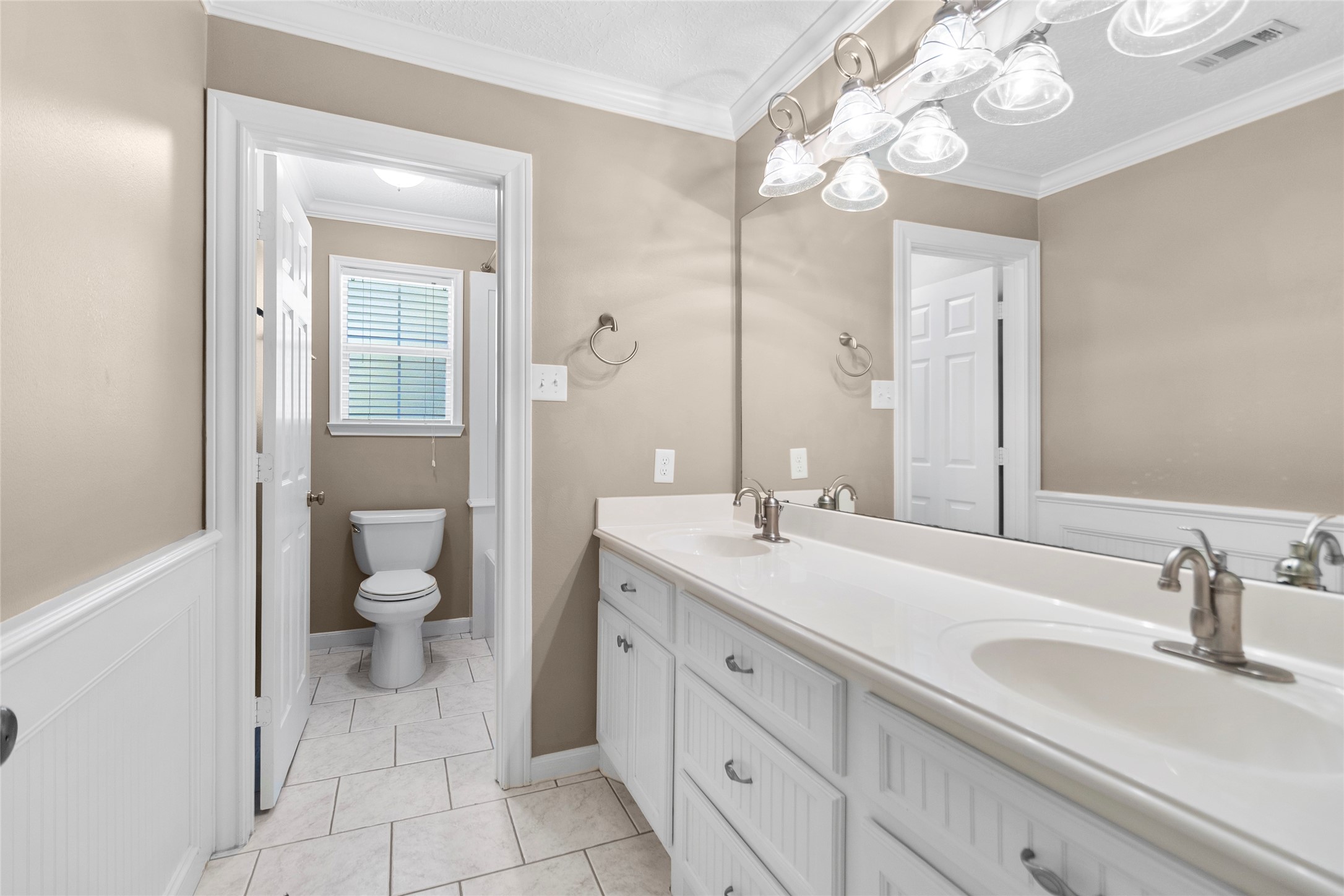 Mornings feel easier in the guest house main bathroom, where an oversized dual-sink vanity offers generous counter space, abundant storage, and a fresh neutral palette.