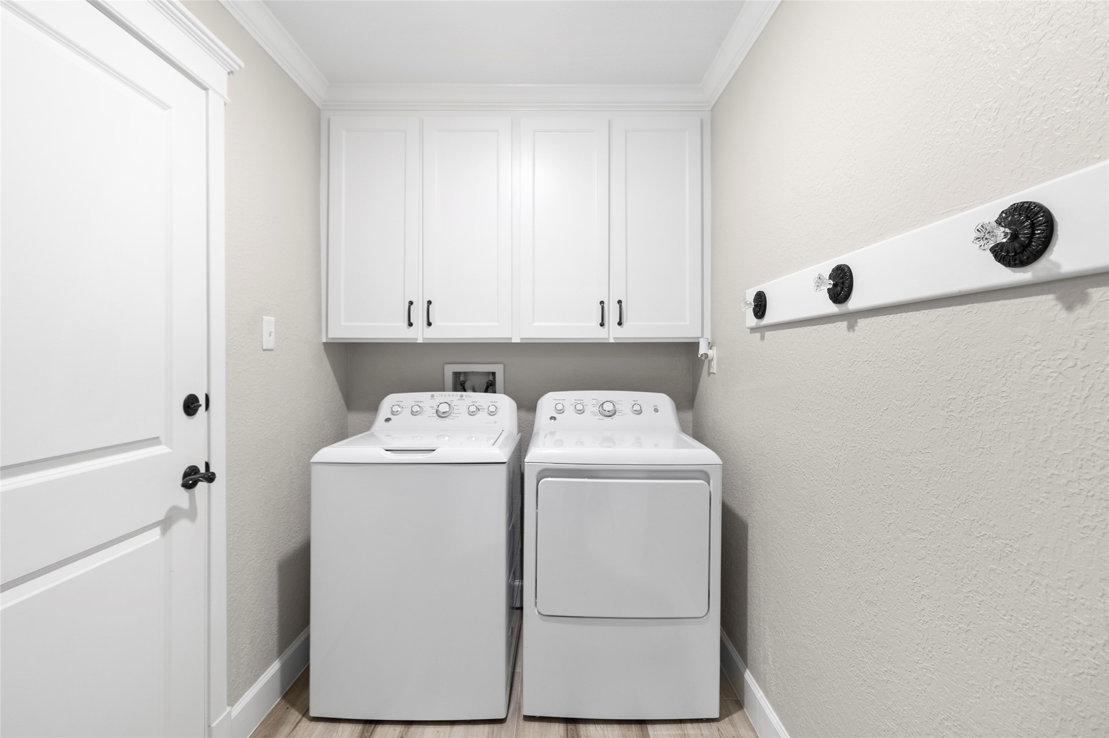Laundry day feels effortless in your dedicated utility room featuring upper cabinetry for added storage and an organized, streamlined layout.