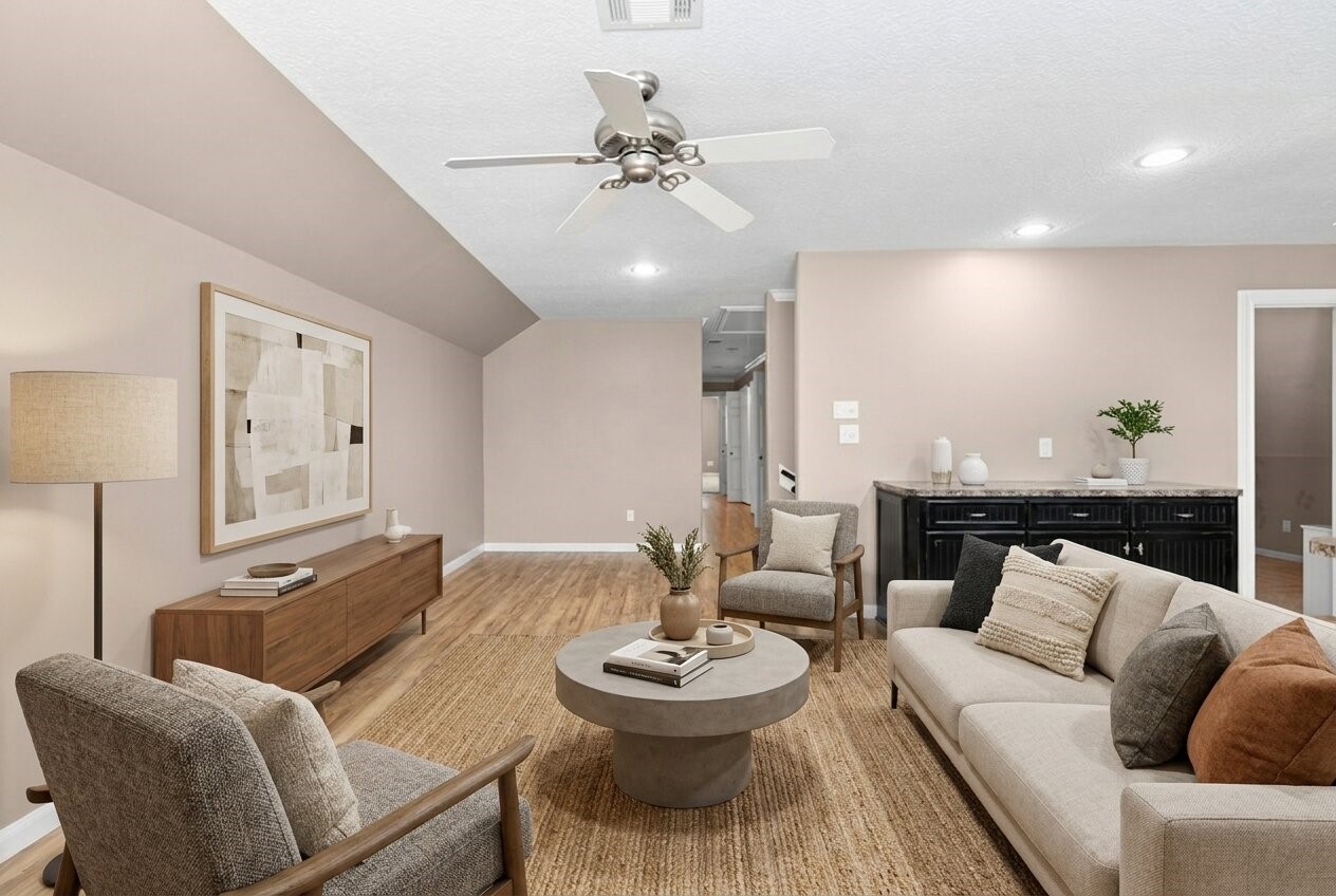 The guest house living room features warm wood-tone flooring and an open-concept layout that flows seamlessly into the kitchen. Soft natural light and a fresh neutral palette make the space easy to personalize. This space has been virtually adjusted using artificial intelligence.