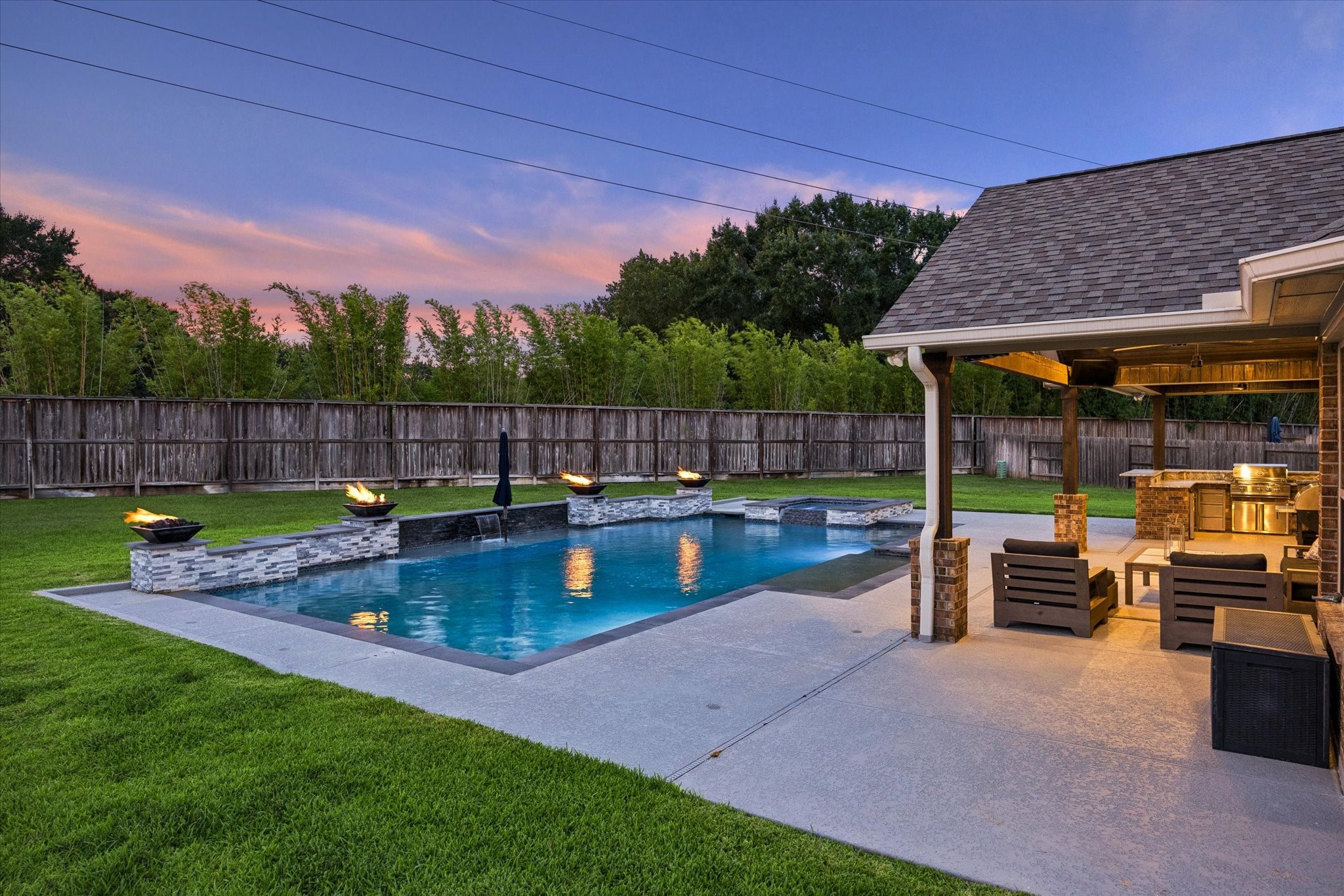 As the sun sets, the glowing pool and illuminated patio transform this space into an unforgettable destination for evening entertaining.