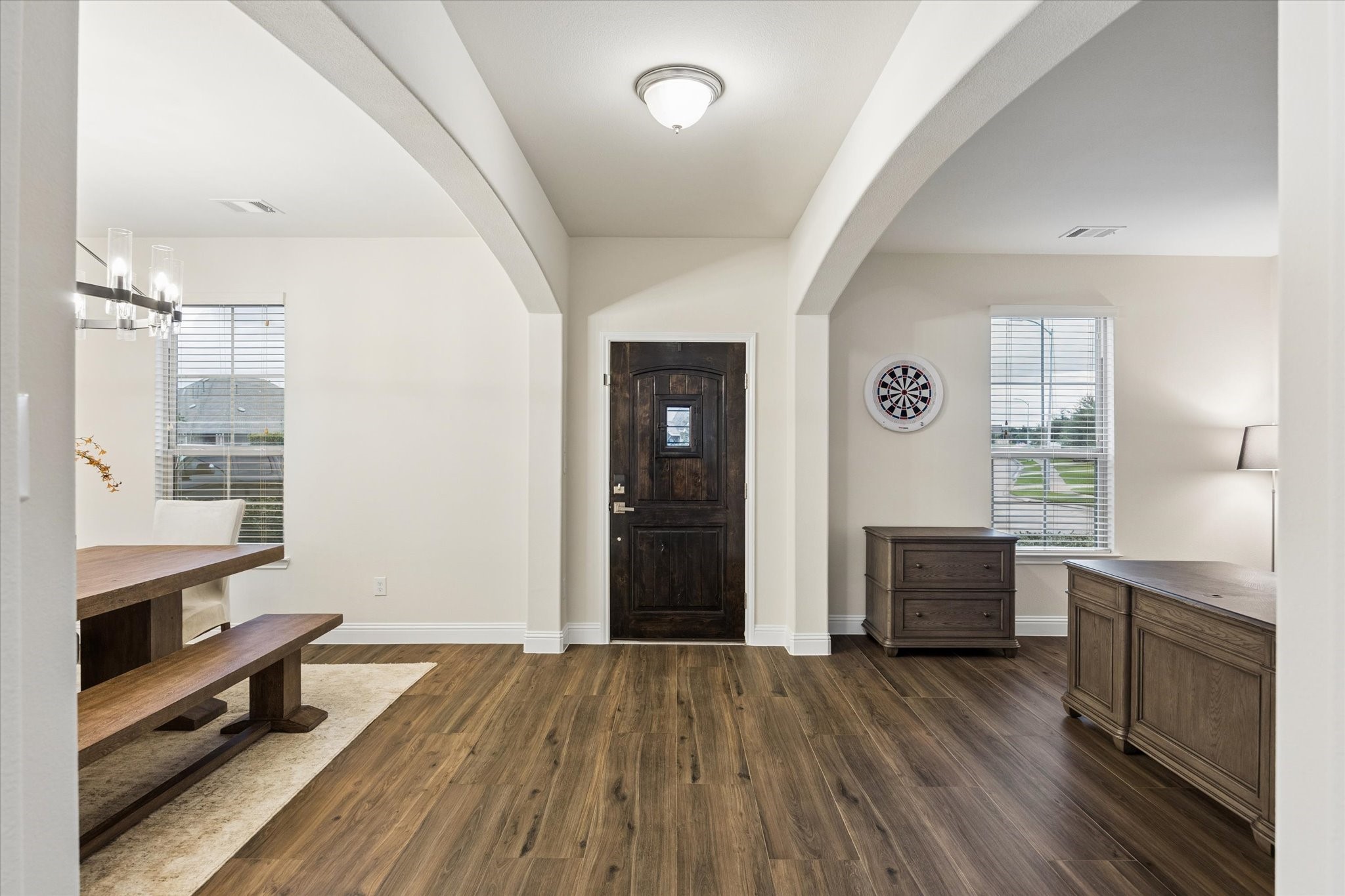 Large white arched openings divide the dining area from the foyer/living space, creating a dramatic but welcoming feel.