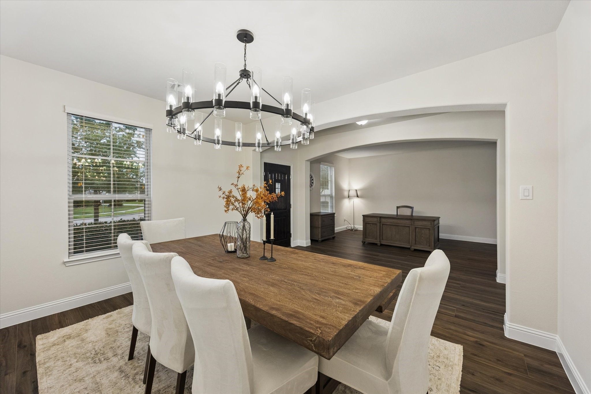 Arched architectural details, neutral finishes, and abundant natural light create a warm, sophisticated setting perfect for both everyday dining and entertaining. Stylish wagon wheel chandelier definitely makes a statement!
