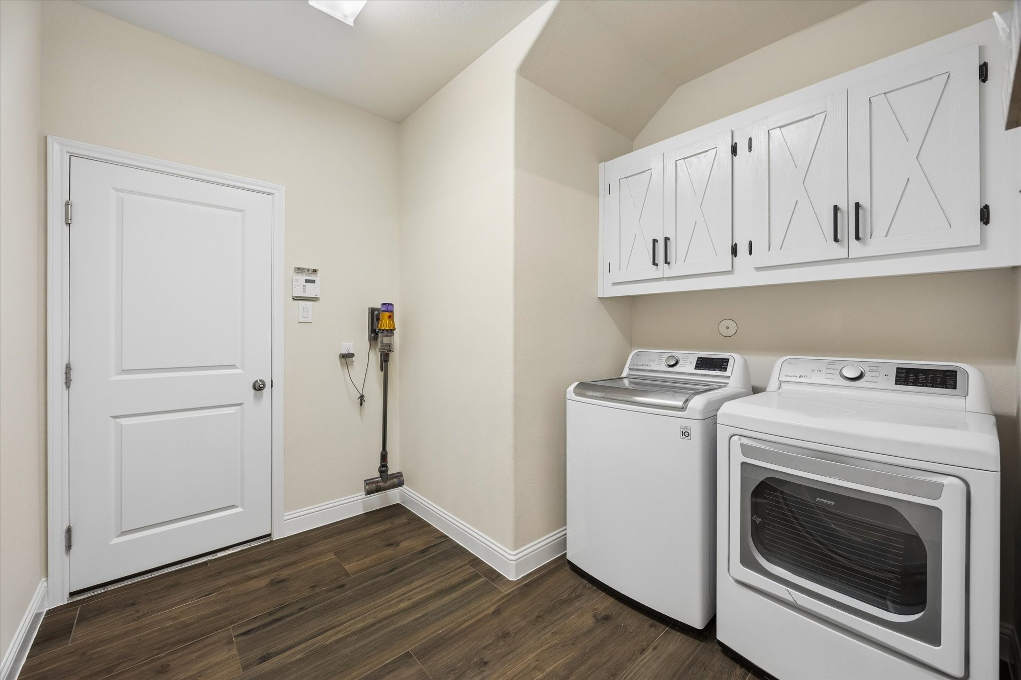 Convenient laundry room featuring more than enough room for a full-size washer and dryer, abundant overhead cabinetry, and durable flooring. The clean, neutral finishes and generous storage provide a practical and organized space for everyday household needs.