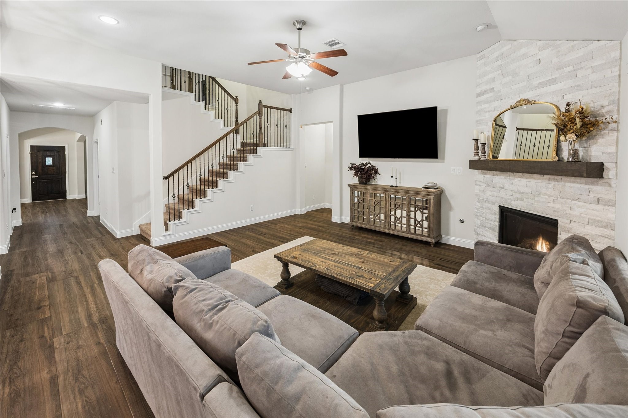 Fantastic living room featuring a striking stone fireplace with a wood mantel, elegant built-in-style furnishings, and a large seating area perfect for gatherings.