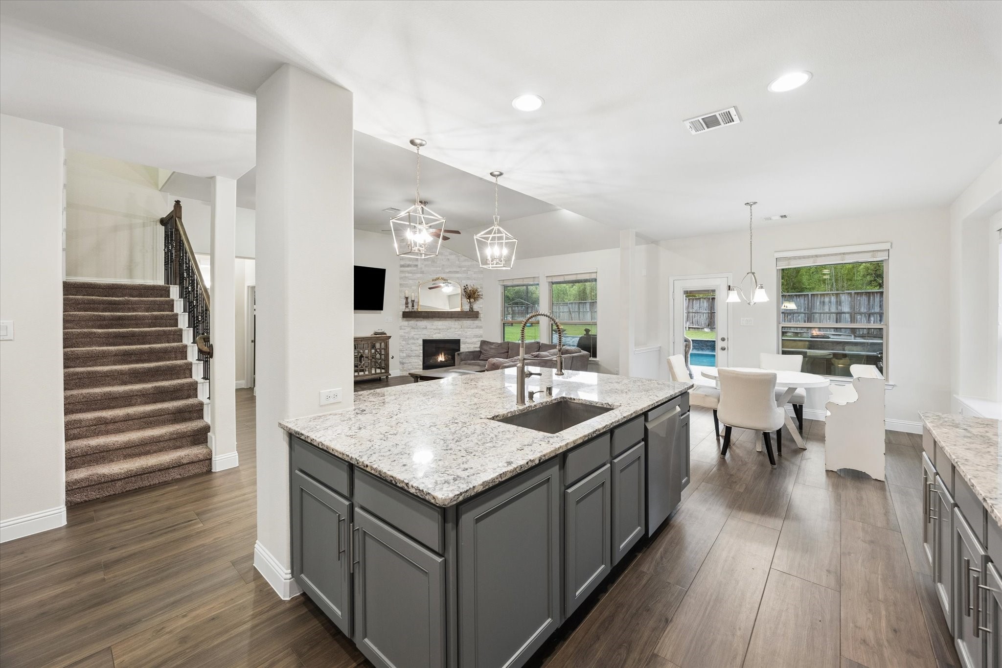 Elegant pendant lighting and recessed fixtures add a polished touch, while the open-concept design flows seamlessly into the main living areas and showcases the home's staircase and generous layout.