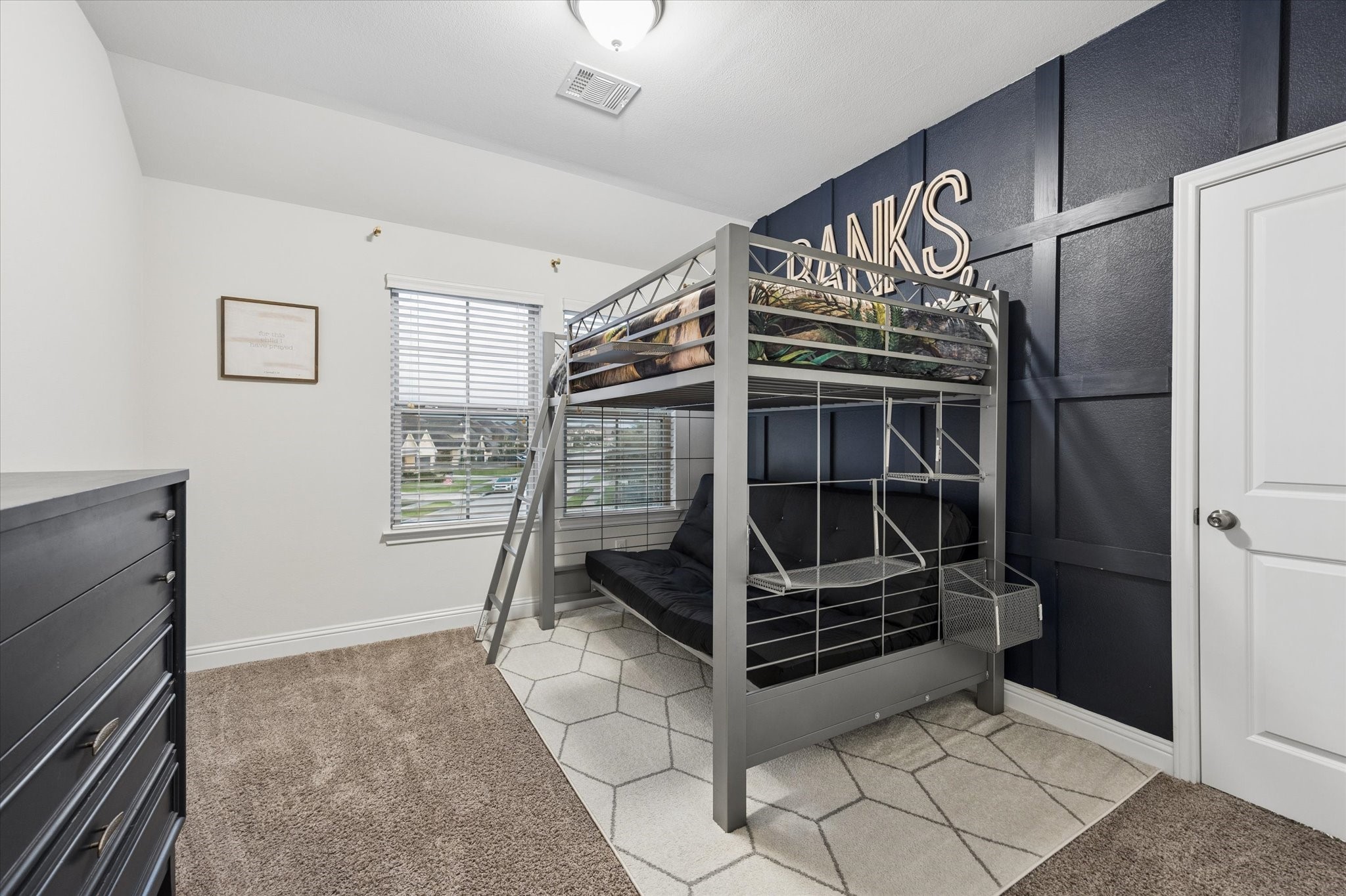This charming bedroom combines function and personality with a bold navy board-and-batten accent wall that creates a striking focal point.