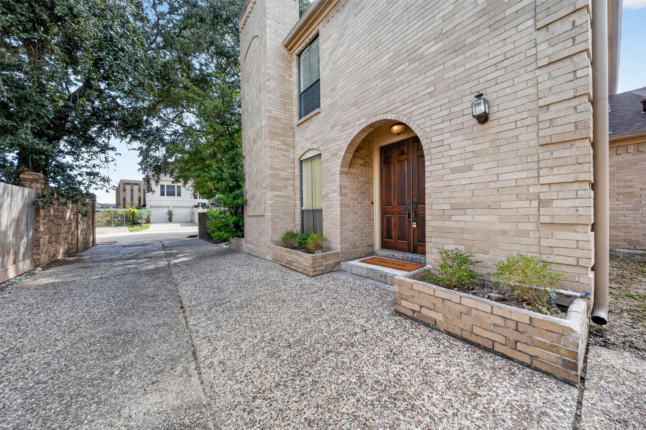 Arched brick entry frames the wood front door, with raised planters along the approach.